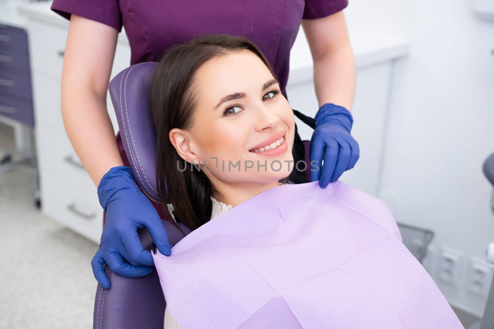 Smiling brunette woman came for teeth checkup in dental clinic.
