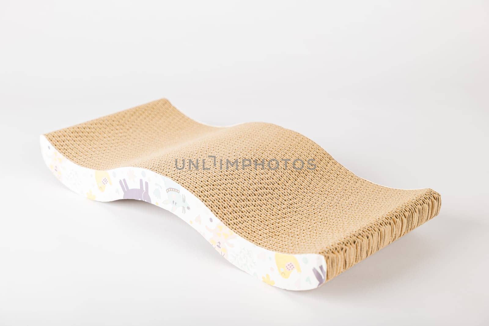 On white backdrop modern abstract cat scratching post showcases its dual purpose as comfy lounge bed made from corrugated cardboard. The cat alertness and playful paw make it a staple for feline care.