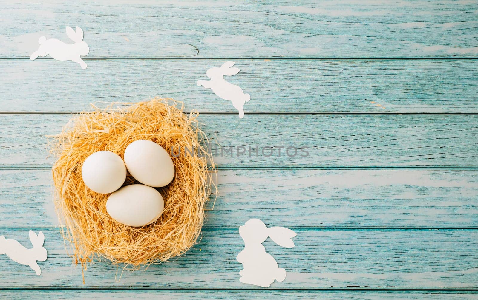 Top view holiday banner background web design white easter eggs in brown nest on blue wooden background with empty copy space, celebration greeting card, overhead, template, Happy Easter Day Concept