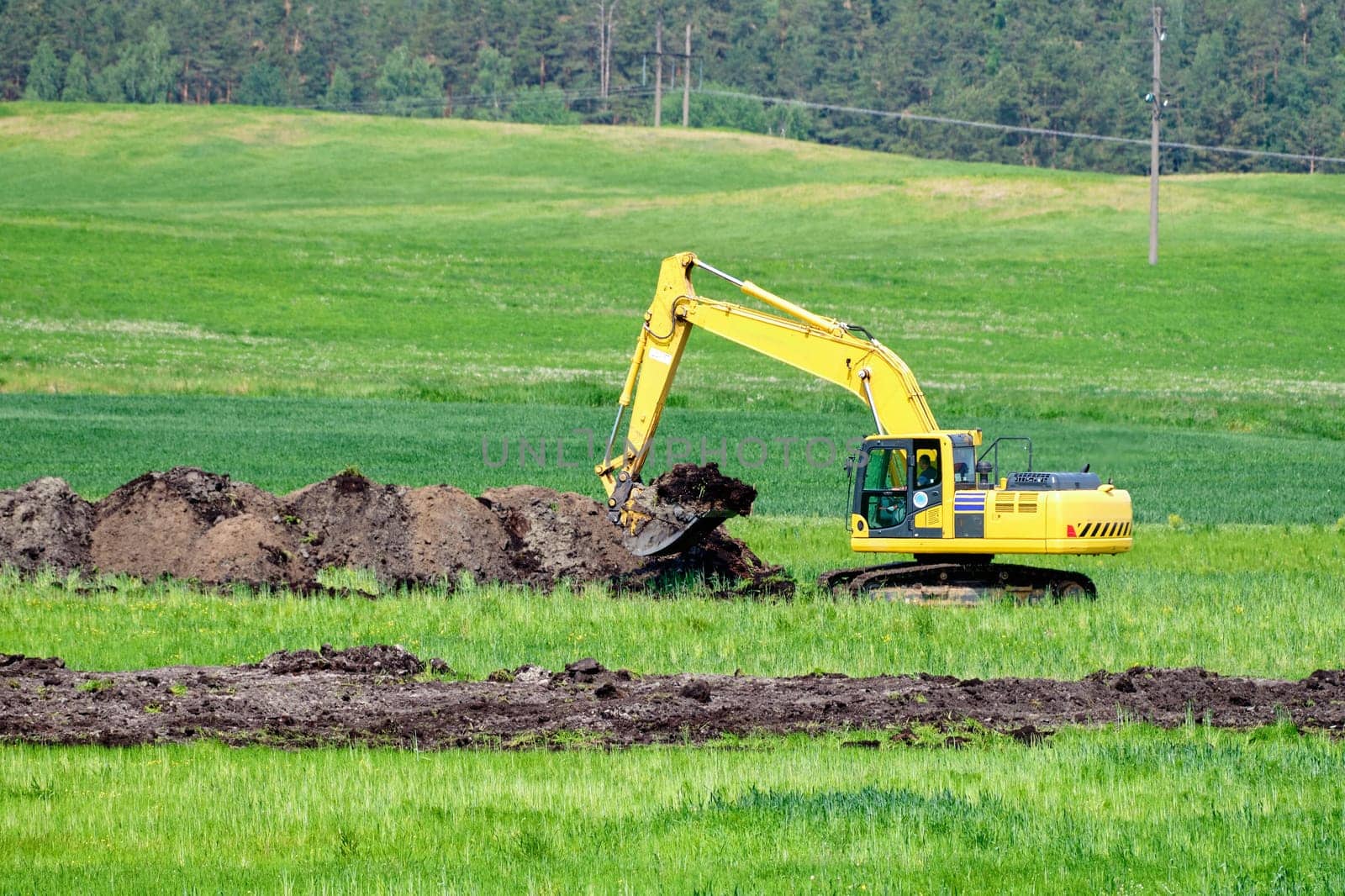 An excavator digs a trench to lay pipes in the soil