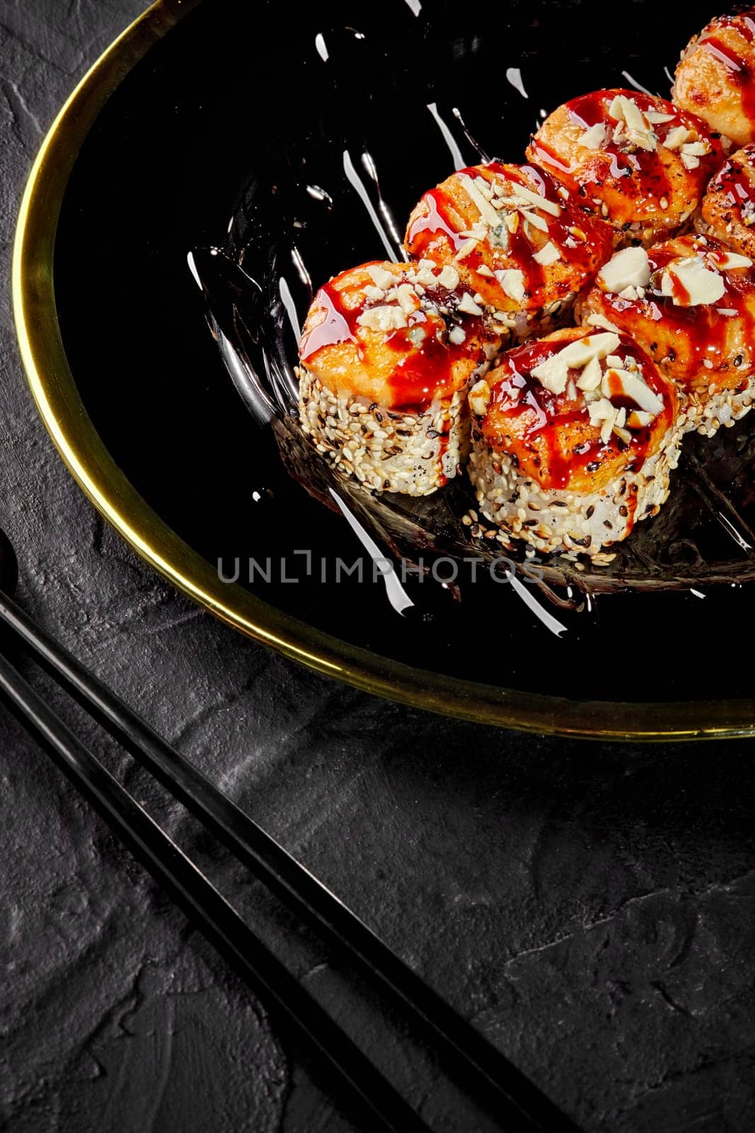 Baked uramaki in sesame with Parmesan crumbs on black and gold platter by nazarovsergey