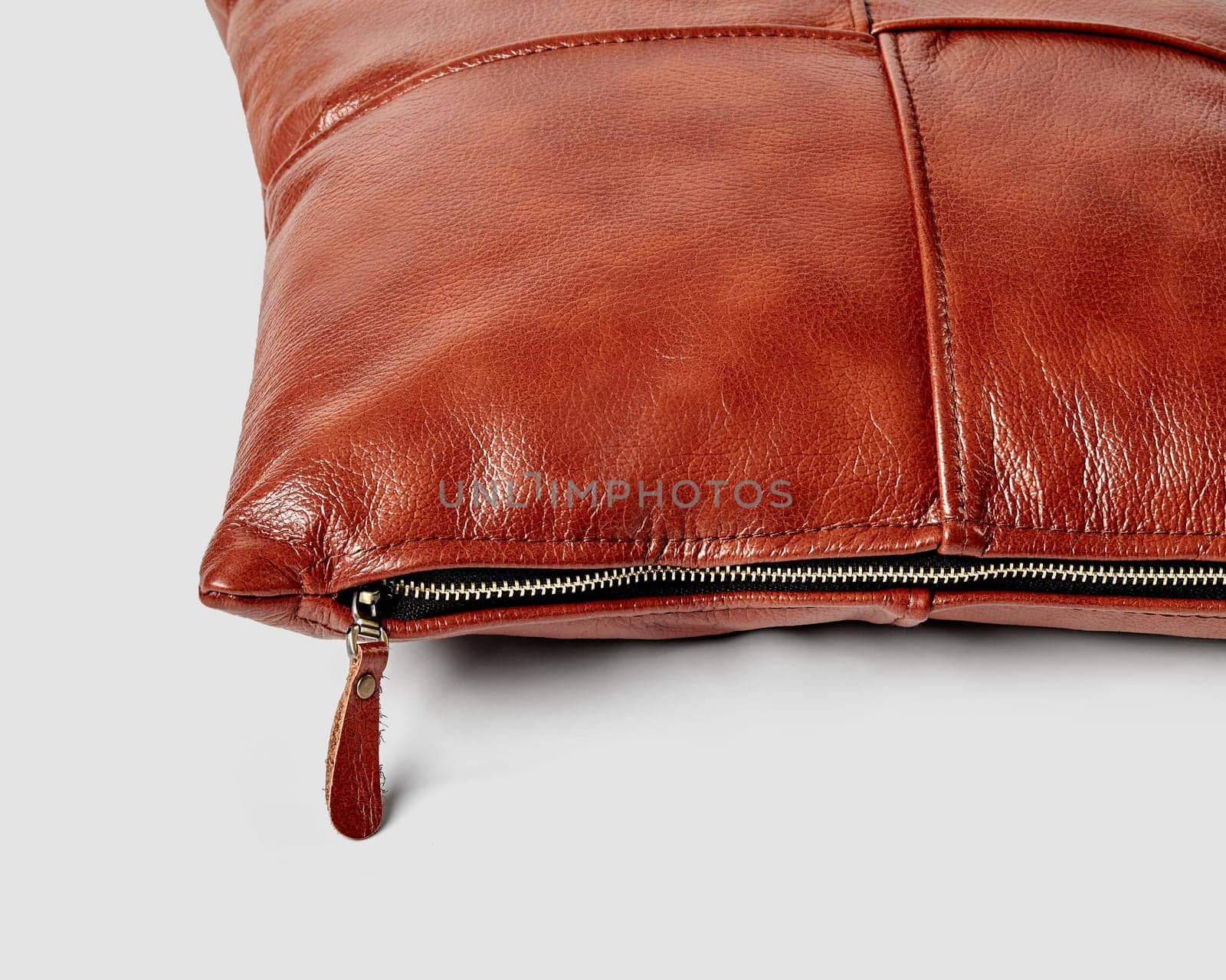 Closeup of handcrafted terracotta leather sofa pillow with side zipper by nazarovsergey