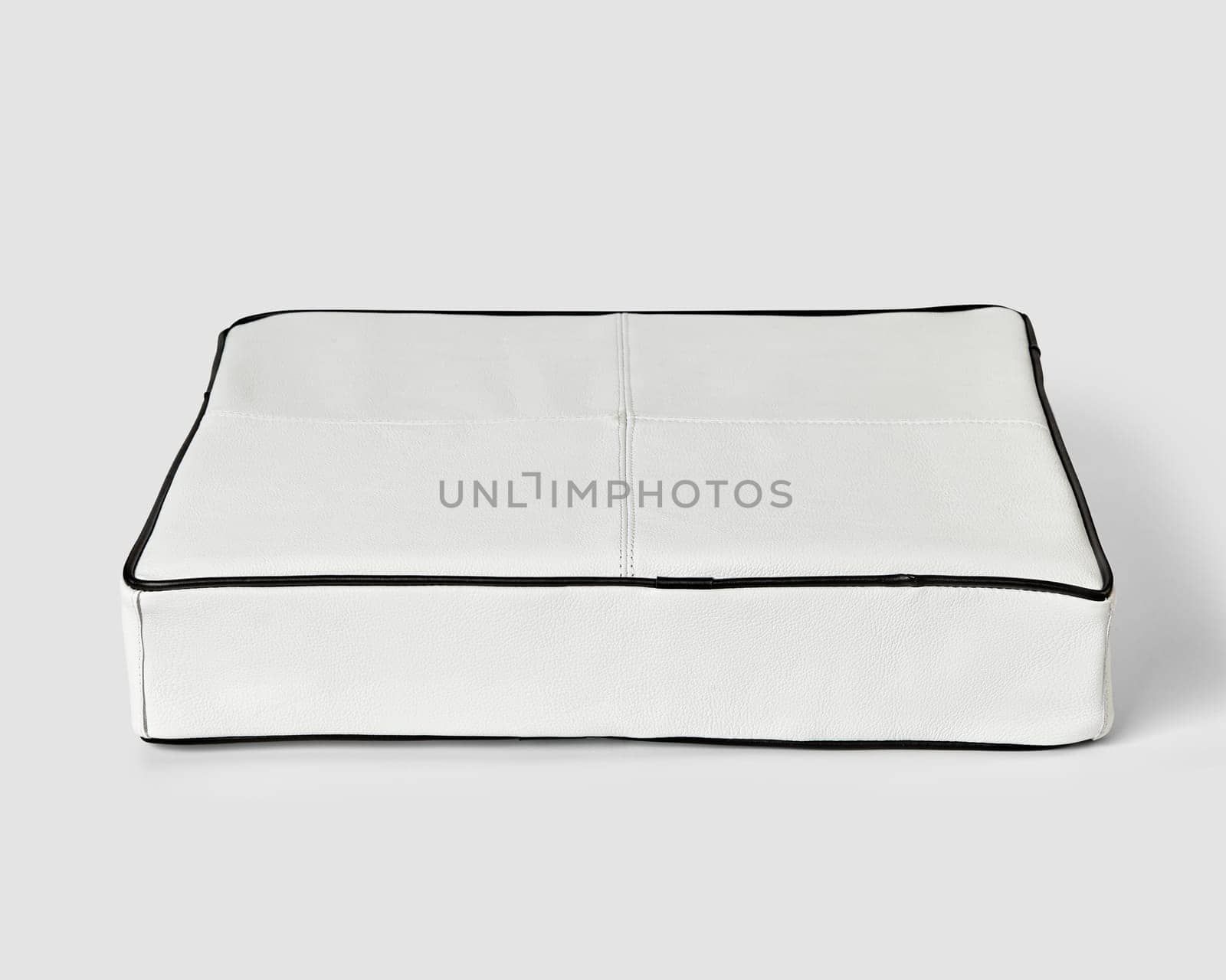 Minimalist soft floor cushion in white leather decorated with contrasting black piping. Stylish item of interior design