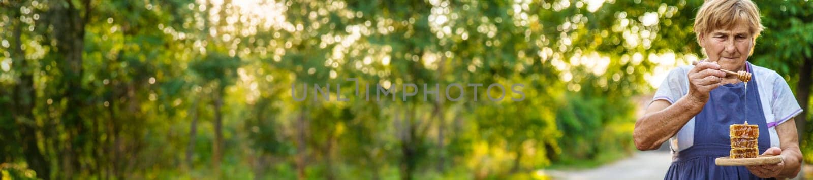 An elderly woman holds honey in her hands, selective focus. People.