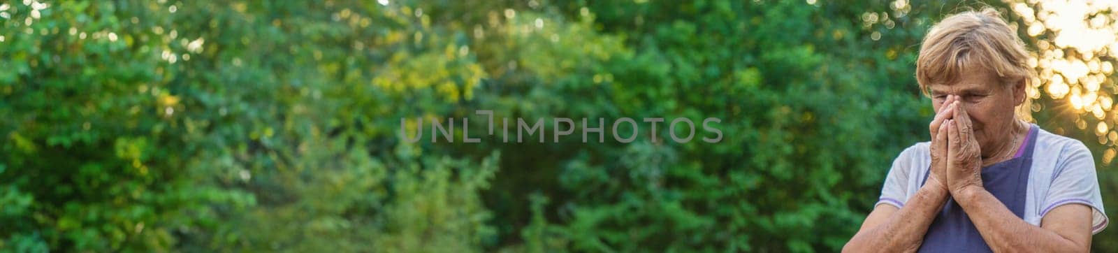 An elderly woman prays in the garden. selective focus. Nature.