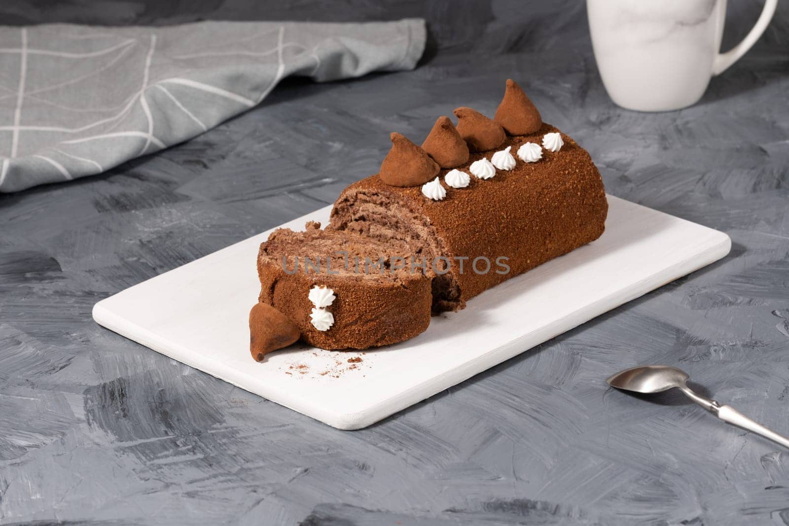 Chocolate roll on a white wooden cutting board.