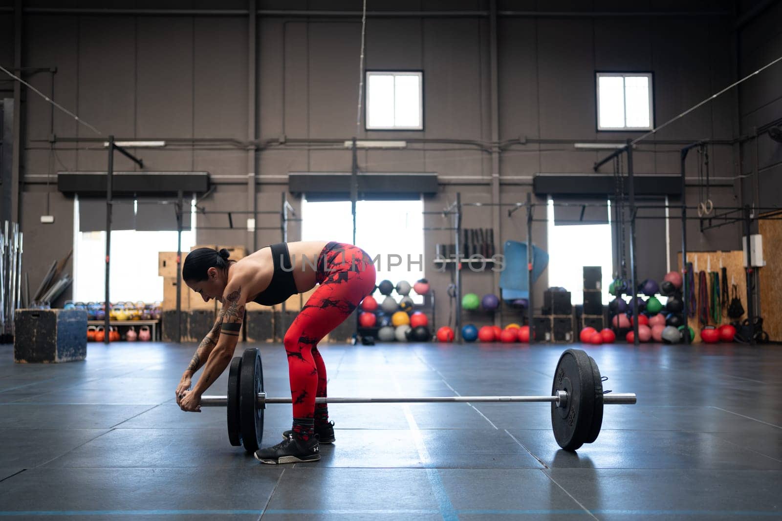 Fit woman preparing bar and lifts to weightlifting in a gym by javiindy