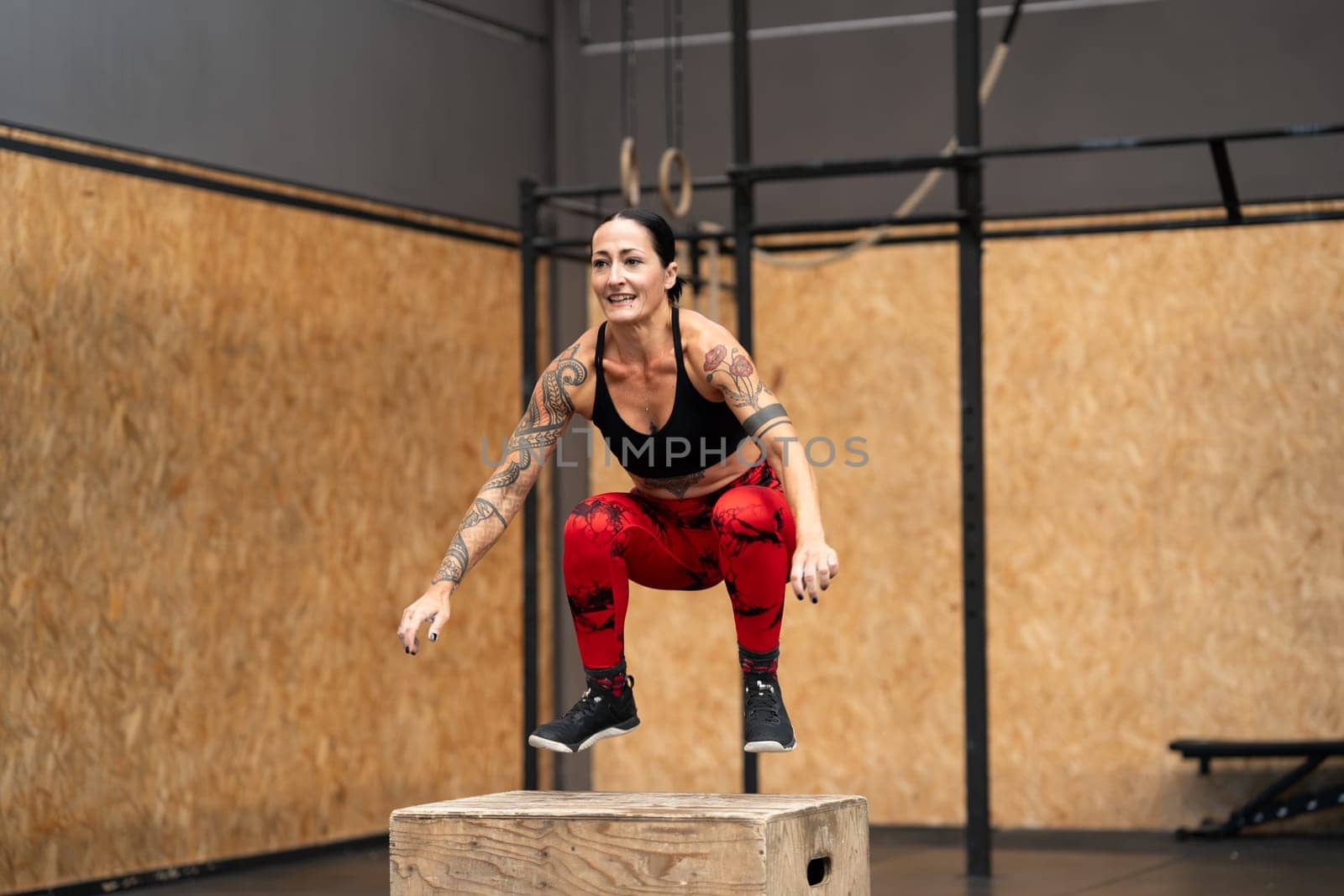 Mature woman jumping into box in a gym by javiindy