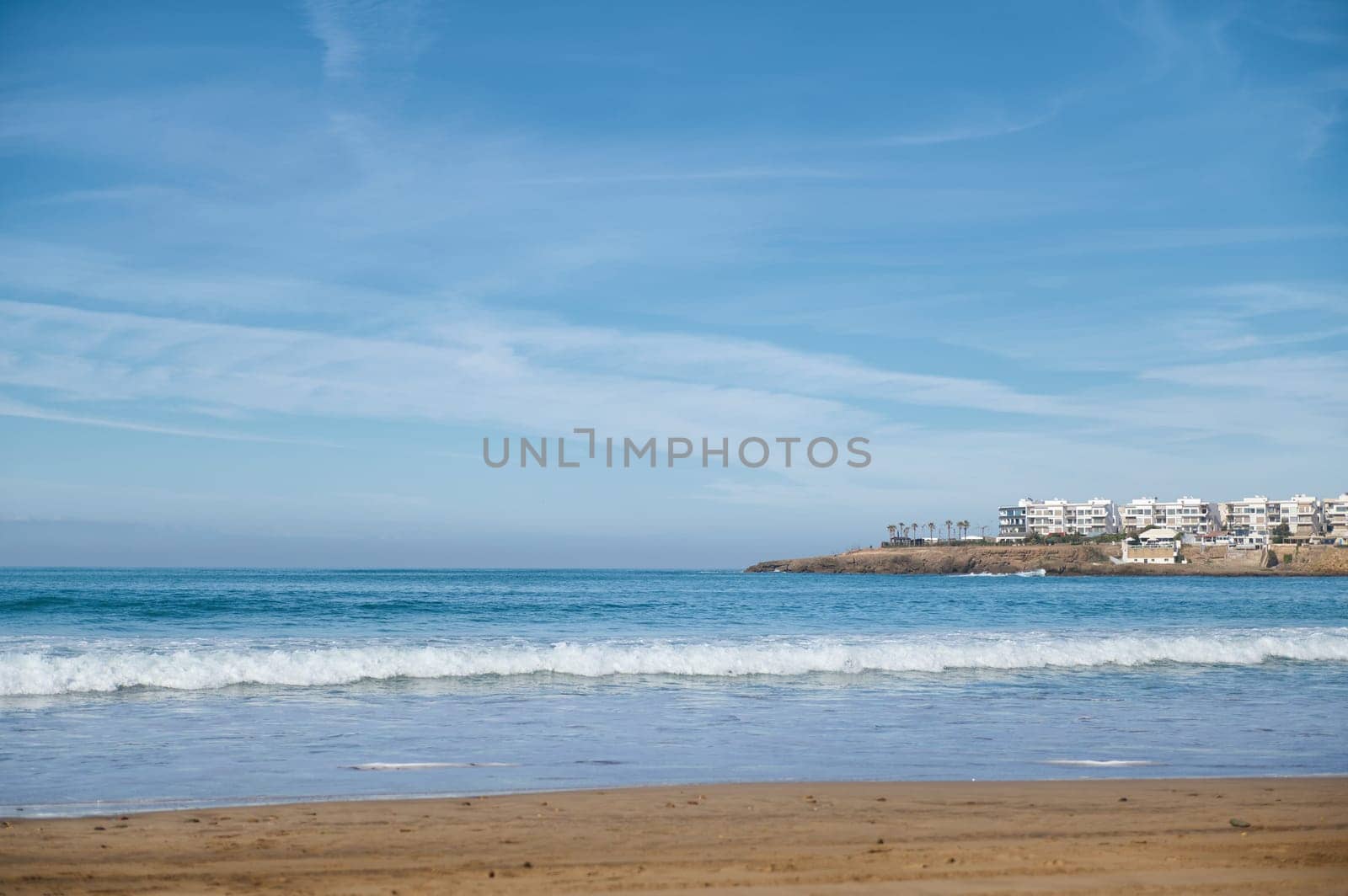 Nature background with seascape. Atlantic ocean. Waves pounding on the sandy beach against the background of white city