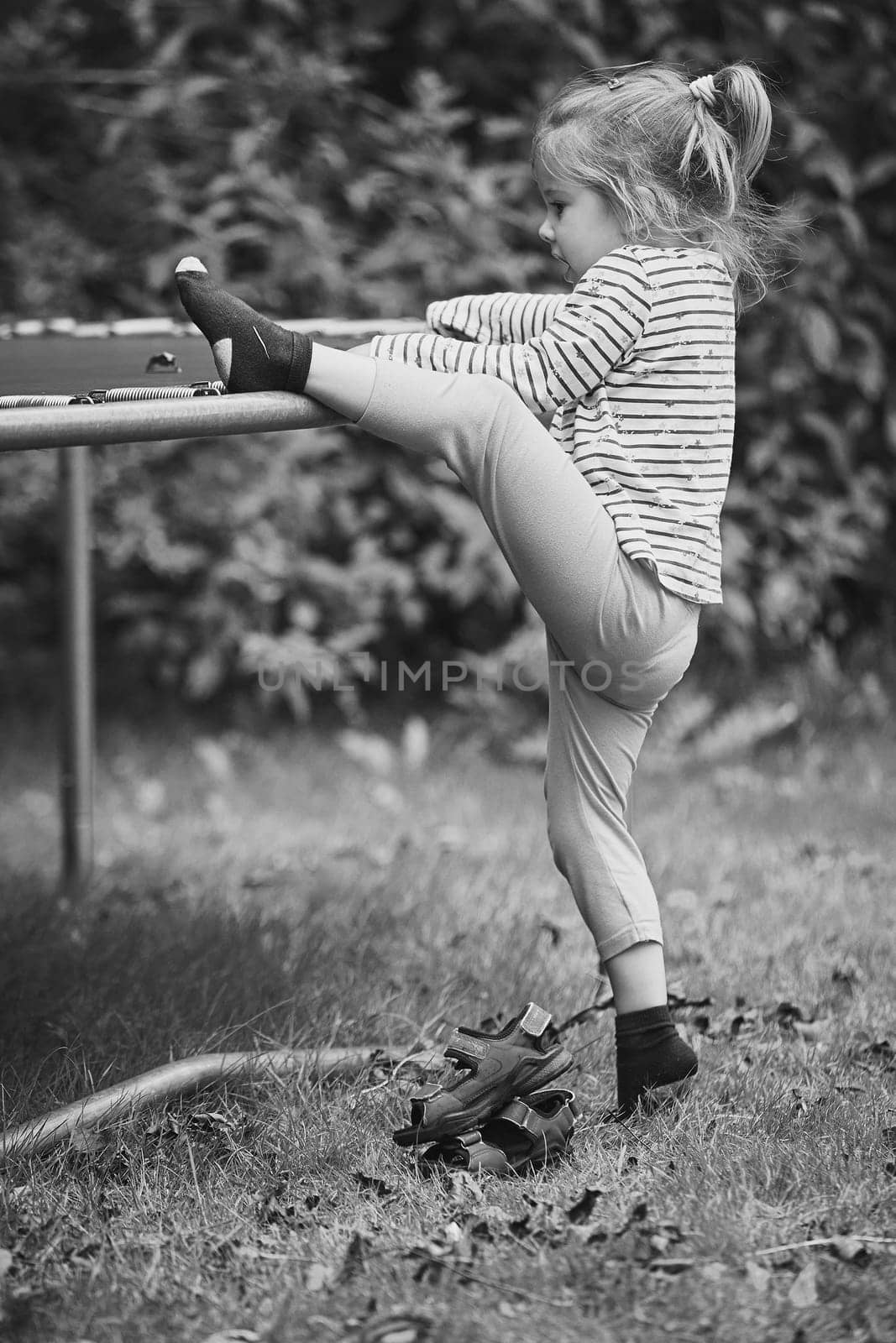 Curious child climbs on a trampoline in the evening garden in Denmark by Viktor_Osypenko