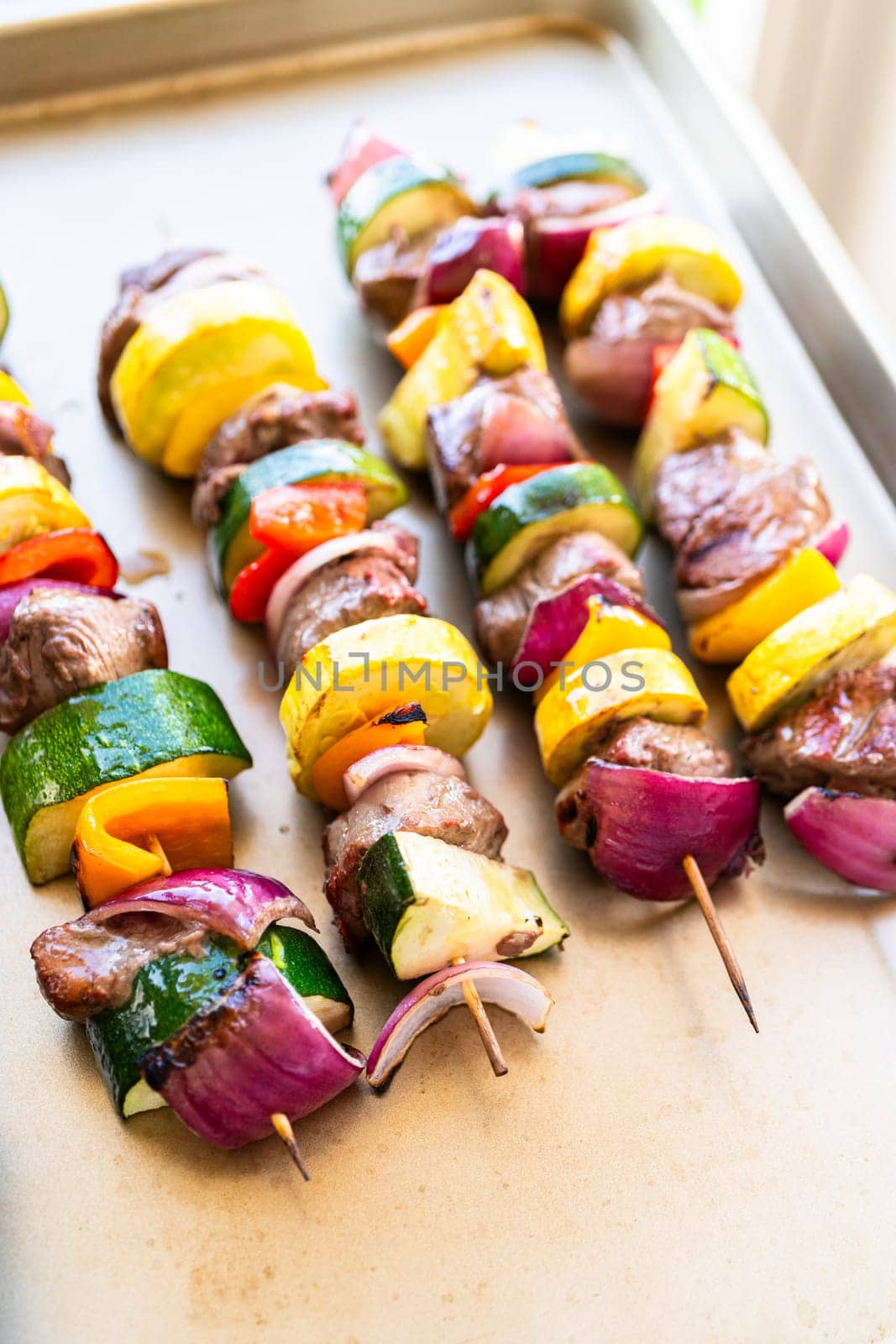 Flavorful beef and colorful veggie skewers, marinated and grilled to perfection, sizzling on a baking sheet.