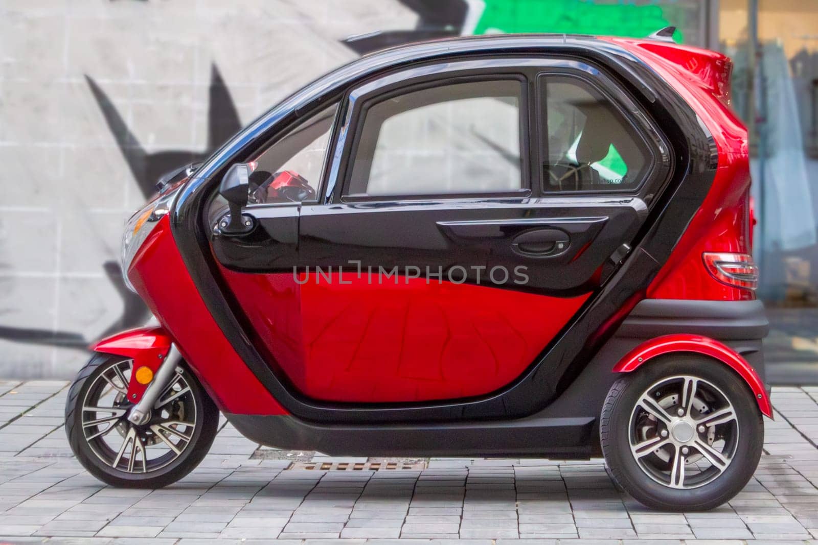 a red three-wheeled car on the background of a painted wall by Maksym