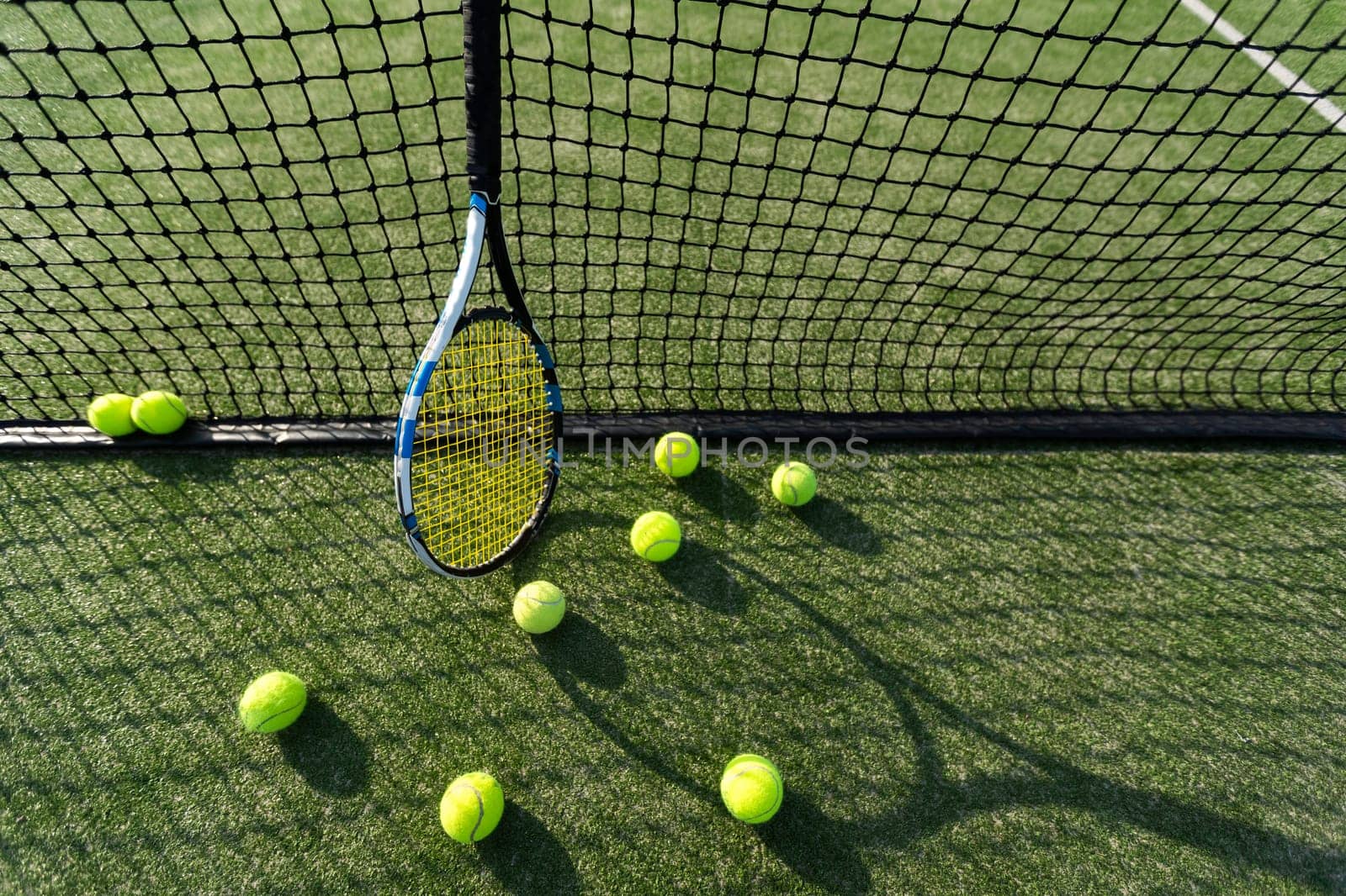 Tennis racket lying on net with tennis ball in hard surface court by Andelov13