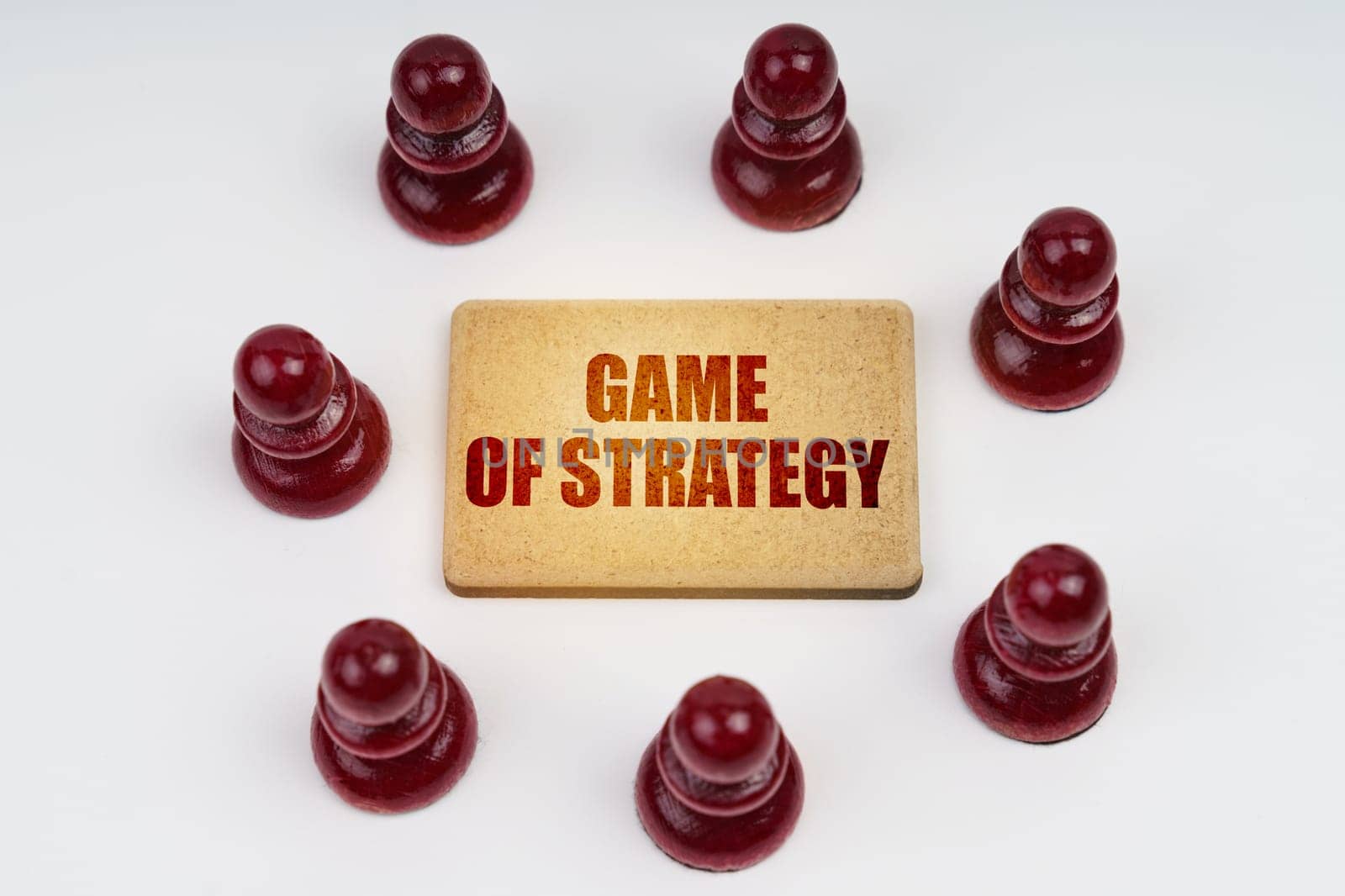 Business concept. On a white background, pawns stand around a sign with the inscription - Game of Strategy