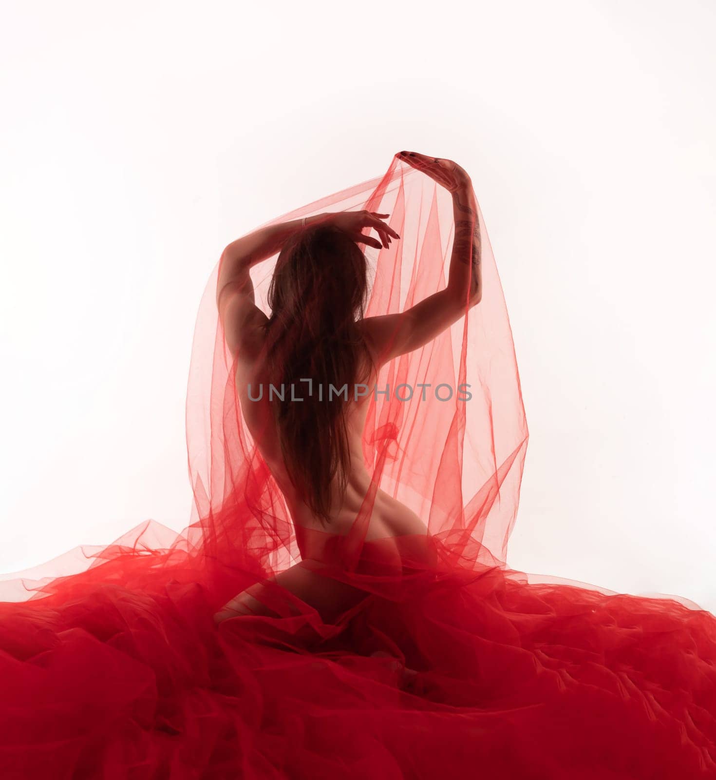 sexy naked girl under a transparent red cloth on a white background erotically dances and poses with beautiful body