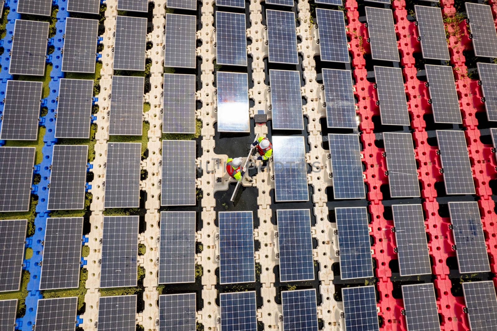 Top view of two technician workers set up or install solar cell panel over the water reservoir as solar farm factory in concept of green energy for good environment.