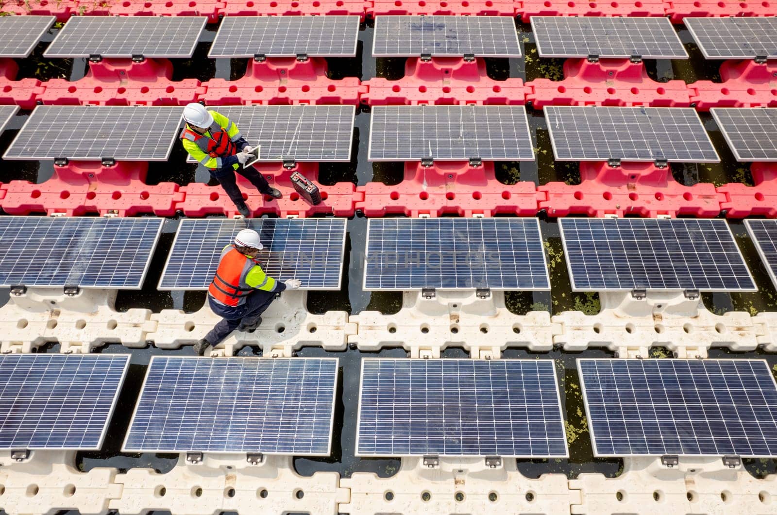 Close up and top side view of two technician workers check and maintenance solar cell panel over the water reservoir as solar farm factory. by nrradmin