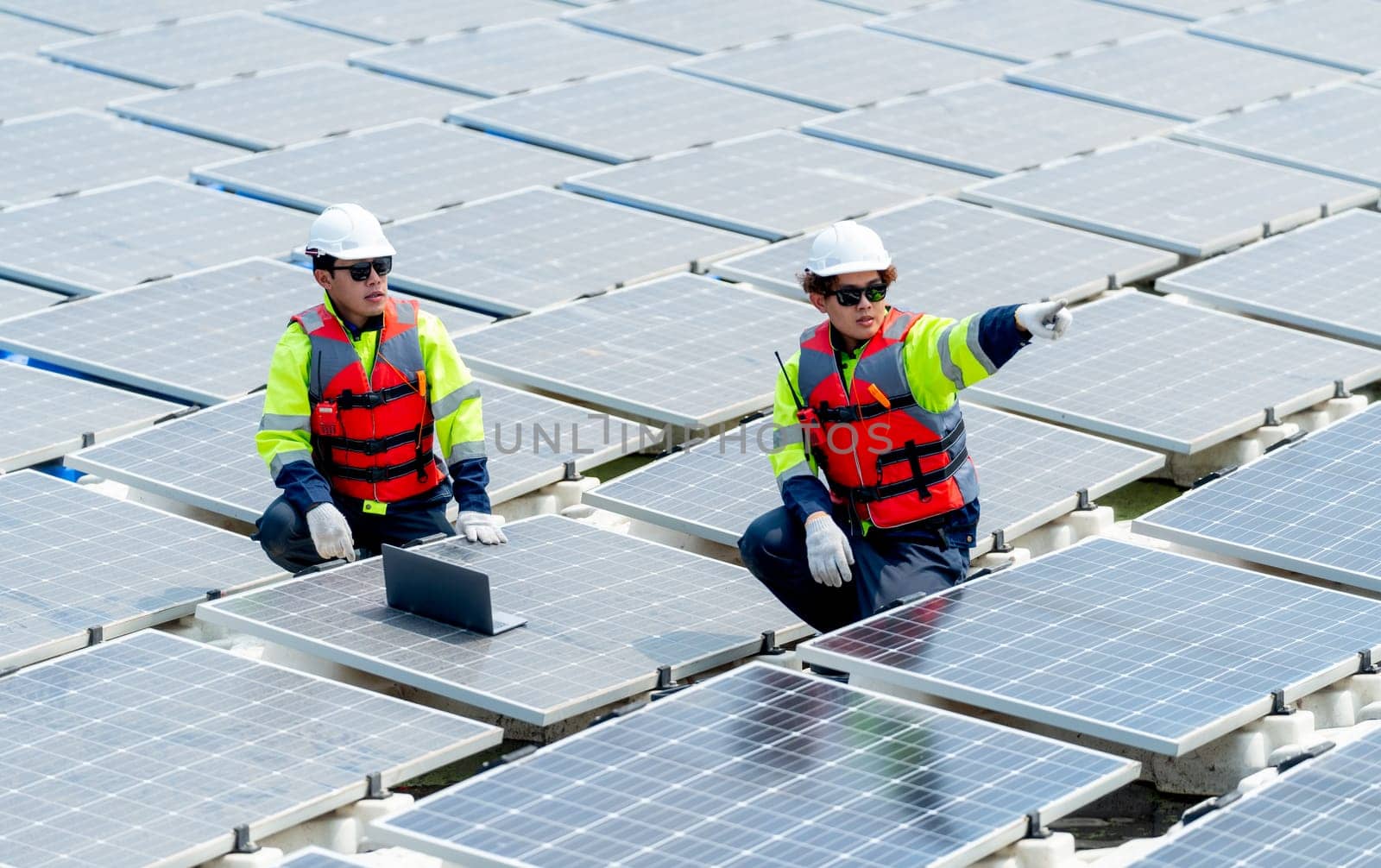One professional technician worker point to the right and discuss with co-worker to work with solar cell panel system.