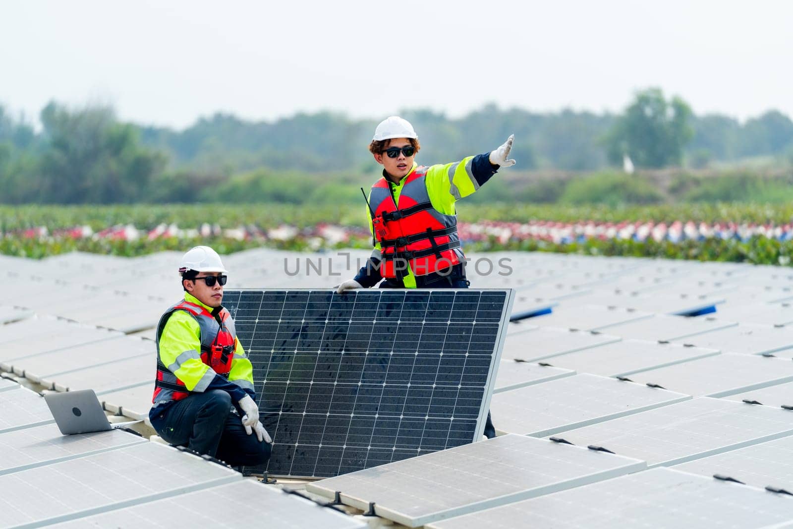 One technician worker sit and look to area that co-worker point to the right and discuss about work of solar cell panel in the network system.