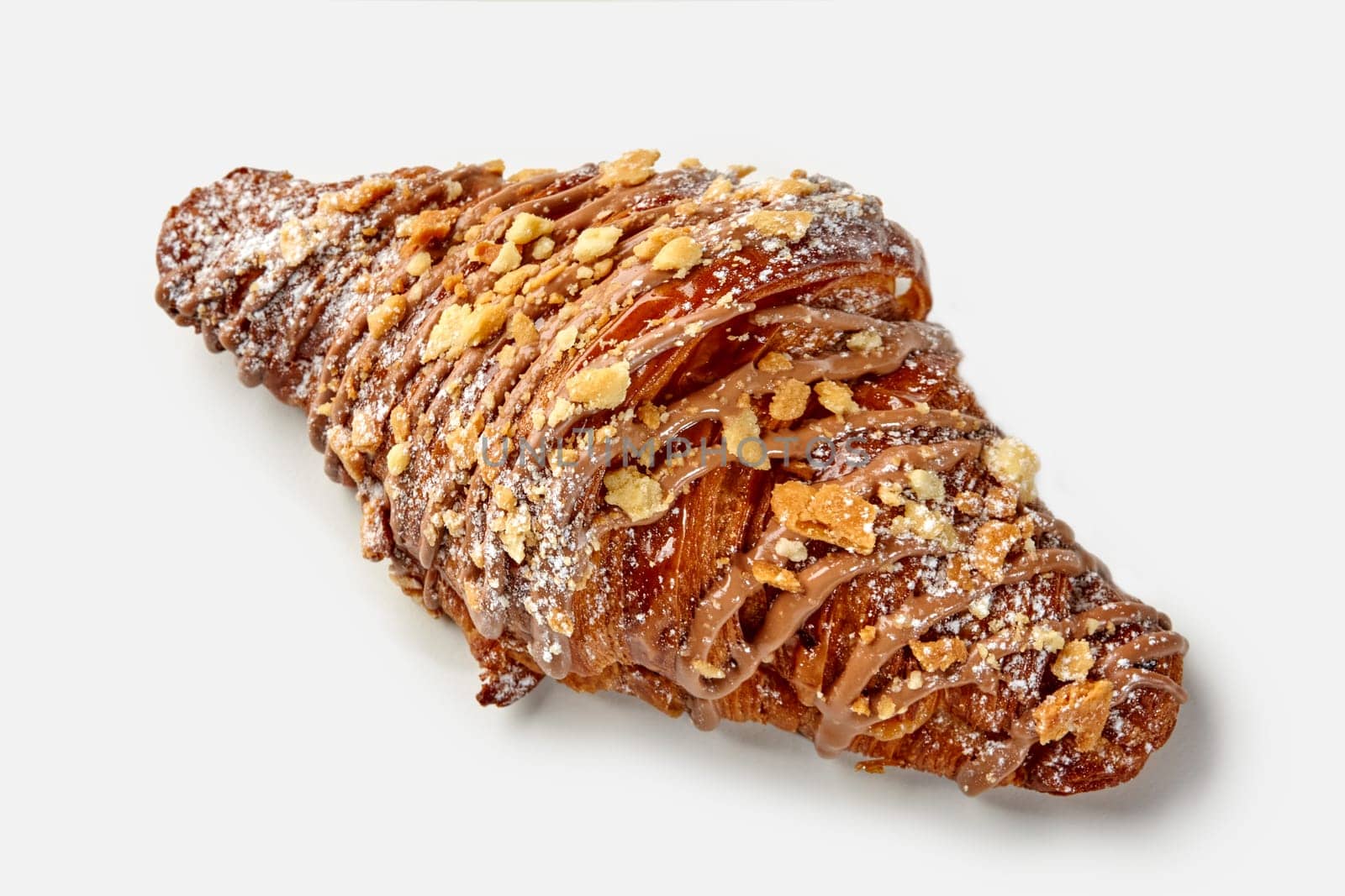 Appetizing golden puff croissant topped with chocolate icing and caramelized crumbles dusted with powdered sugar, isolated on white background. Classic French pastries