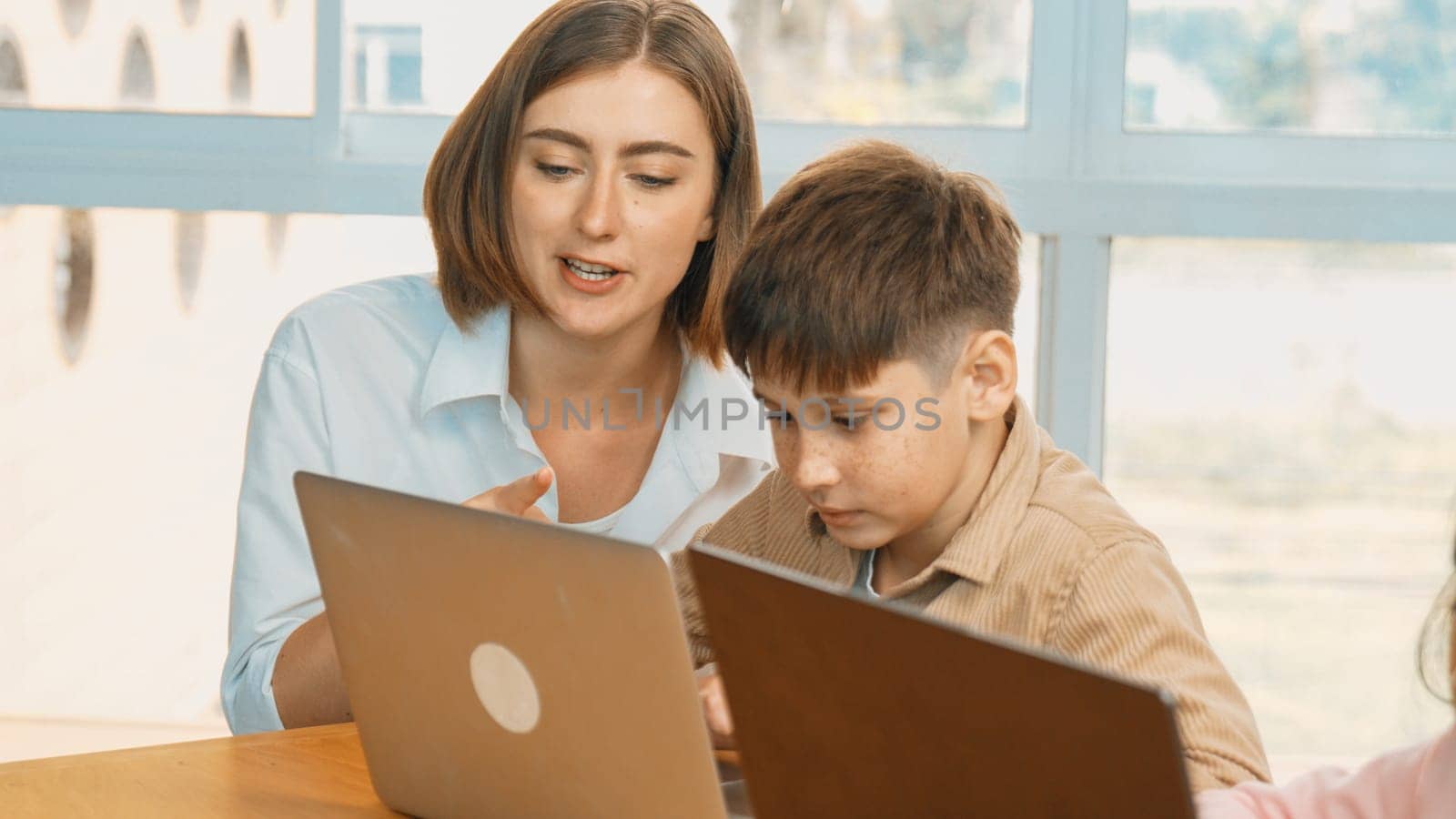 Smart boy coding program or learning prompt at STEM technology class. Caucasian student study about programing system while professional teacher looking at screen and checking digital code. Erudition.