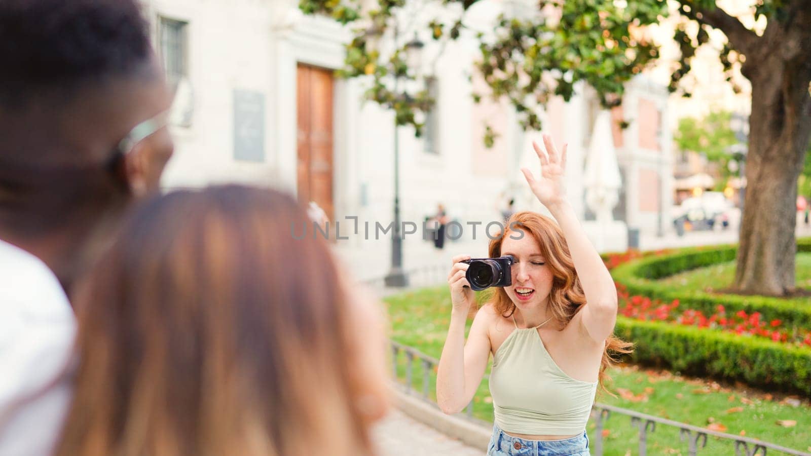 Woman with a camera organising a group of friends to take a photo int he street