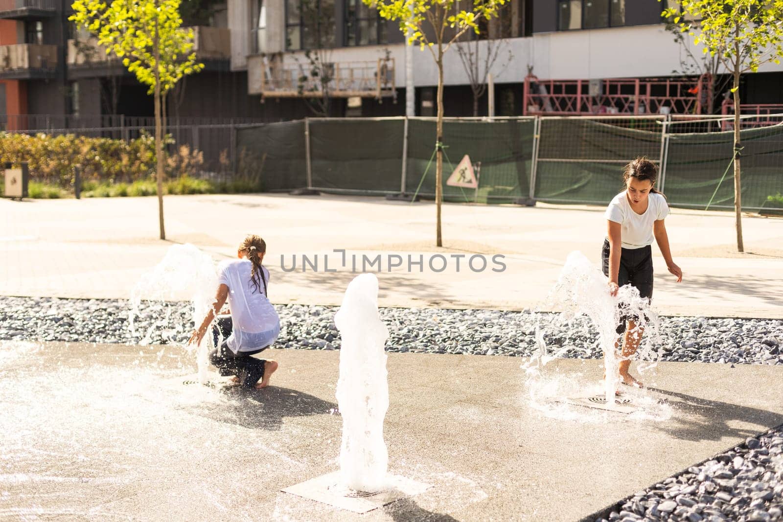 life of children in a modern city - little girl having fun with fountains by Andelov13