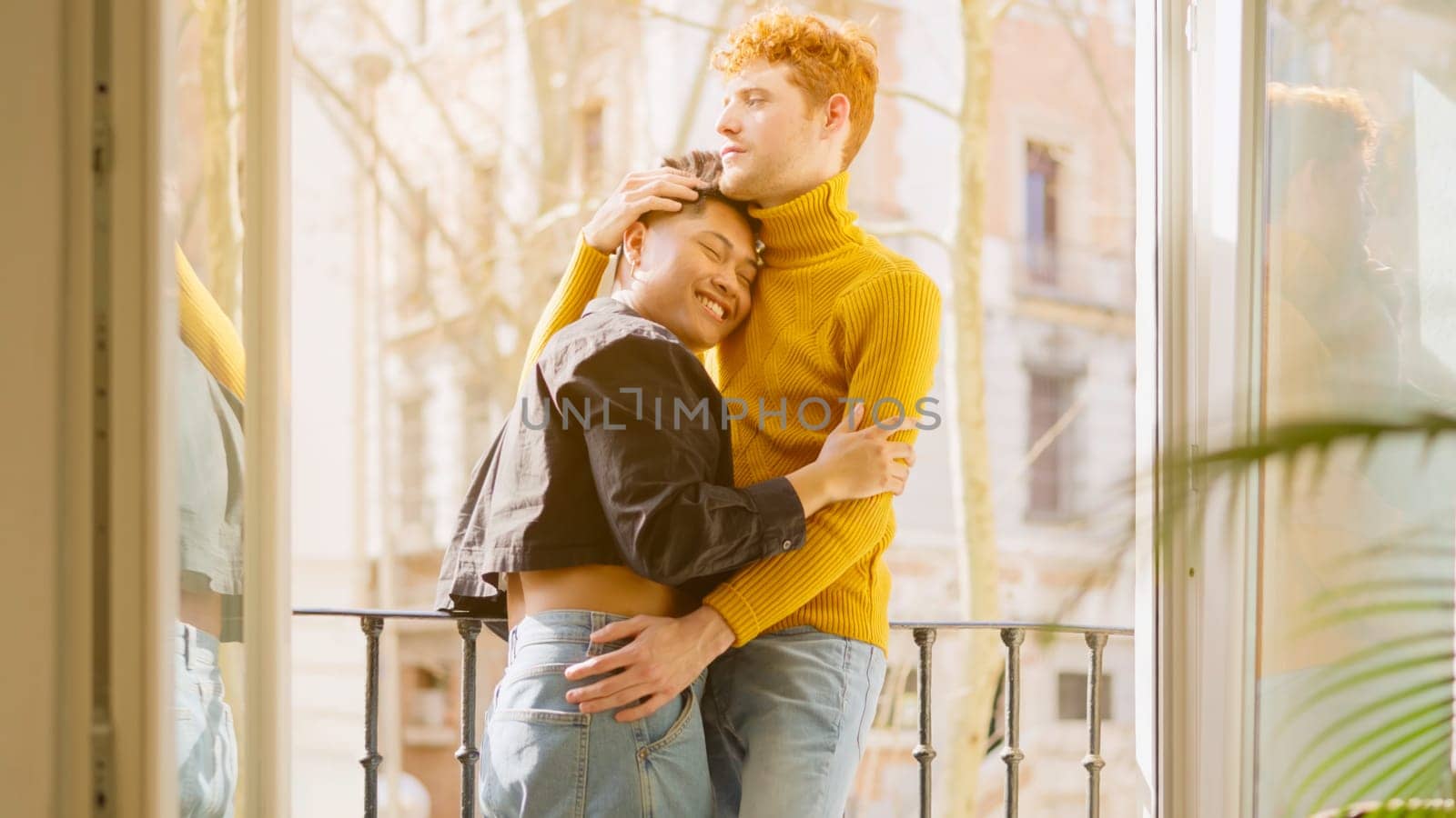 Tender scene of a happy and young gay couple in a balcony at home