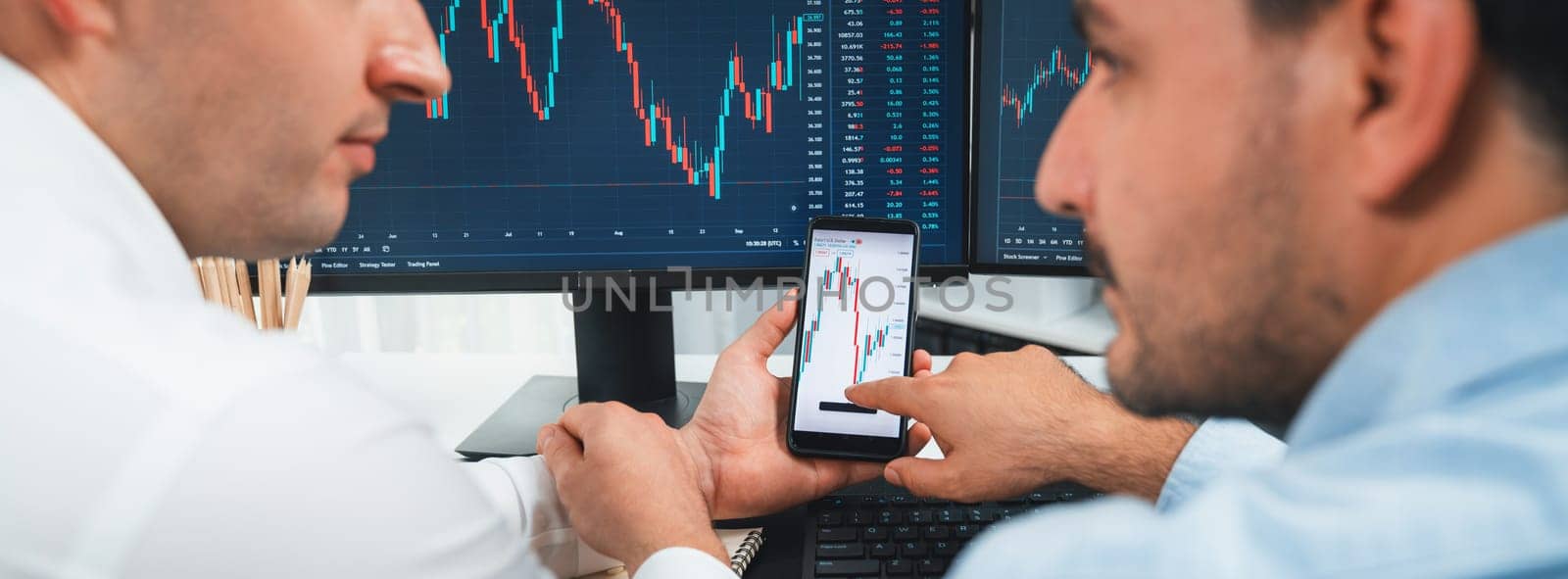 Stock exchange traders pointing lowest chart stage on dynamic graph with smartphone on panorama view, analyzing comparing with monitor and phone. Concept of discussing financial technology. Sellable.