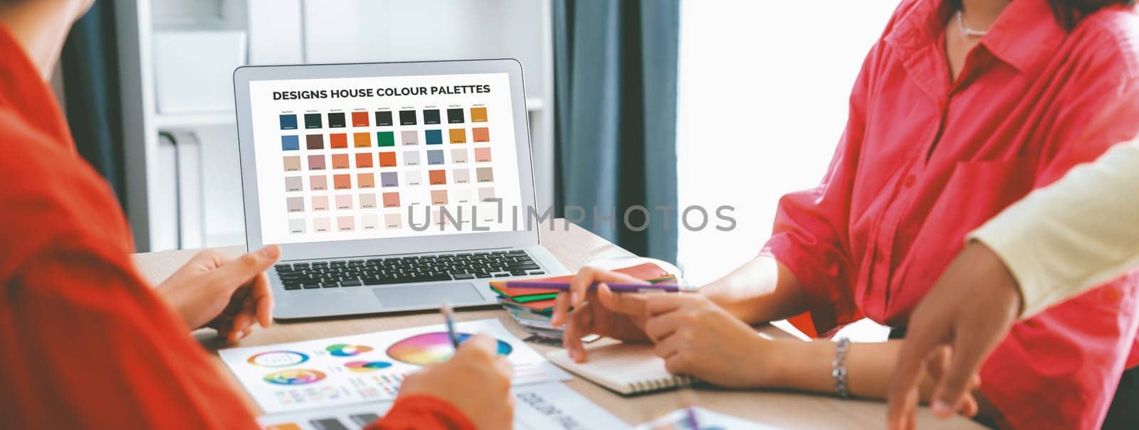 A portrait of creativity graphic designer team select appropriate color for the project by using laptop on table with equipment and designing tool scatter around at modern office. Closeup. Variegated.