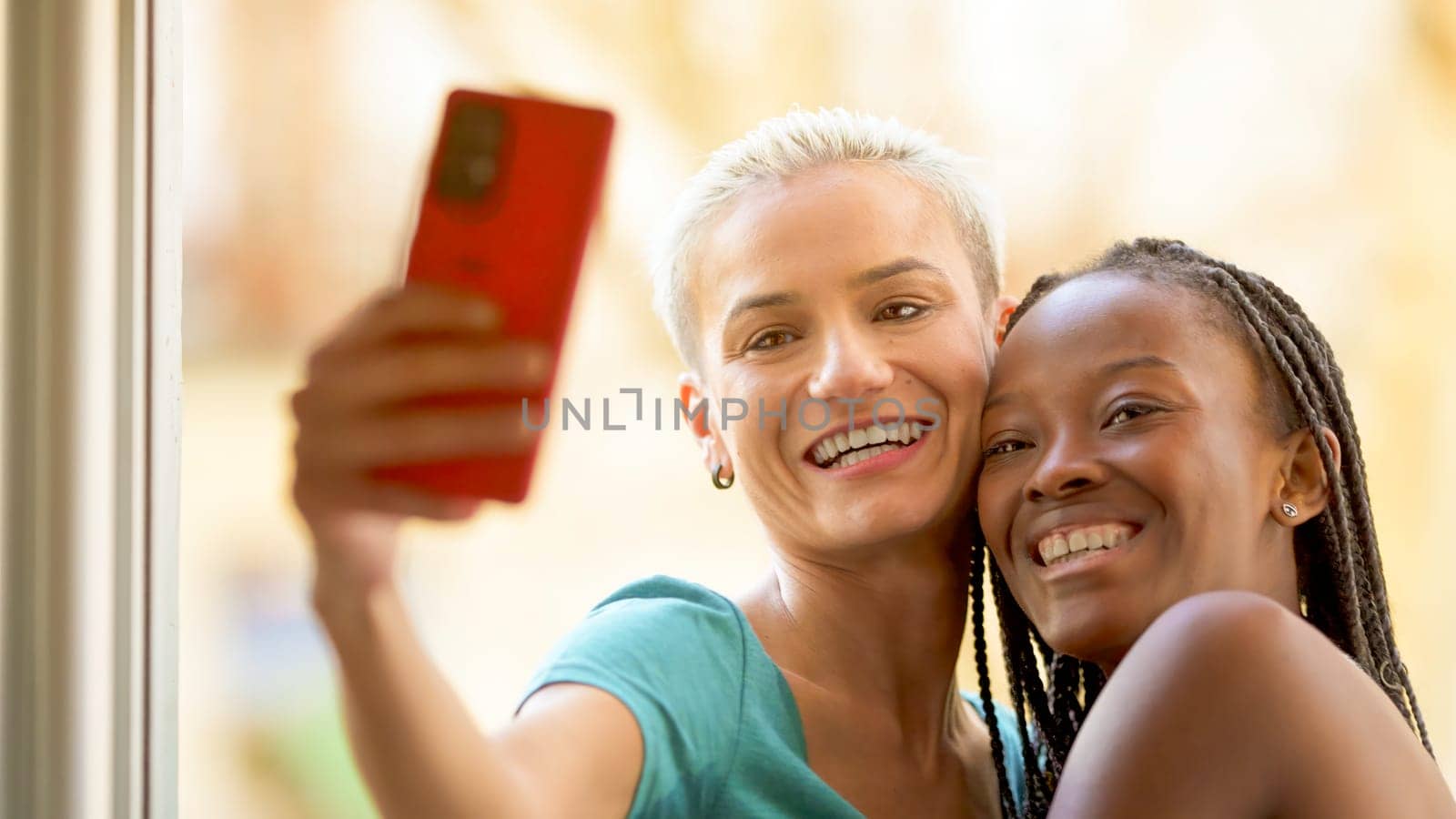 Lesbian couple taking a selfie while smiling on a balcony