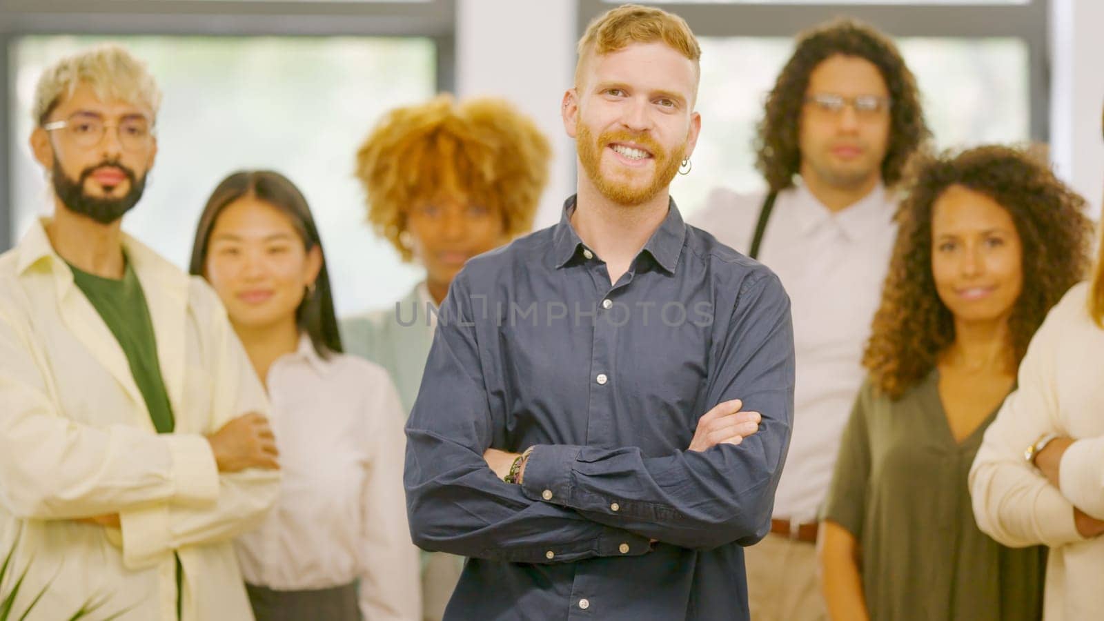Man smiling at camera and standing proud leading a teamwork in the office