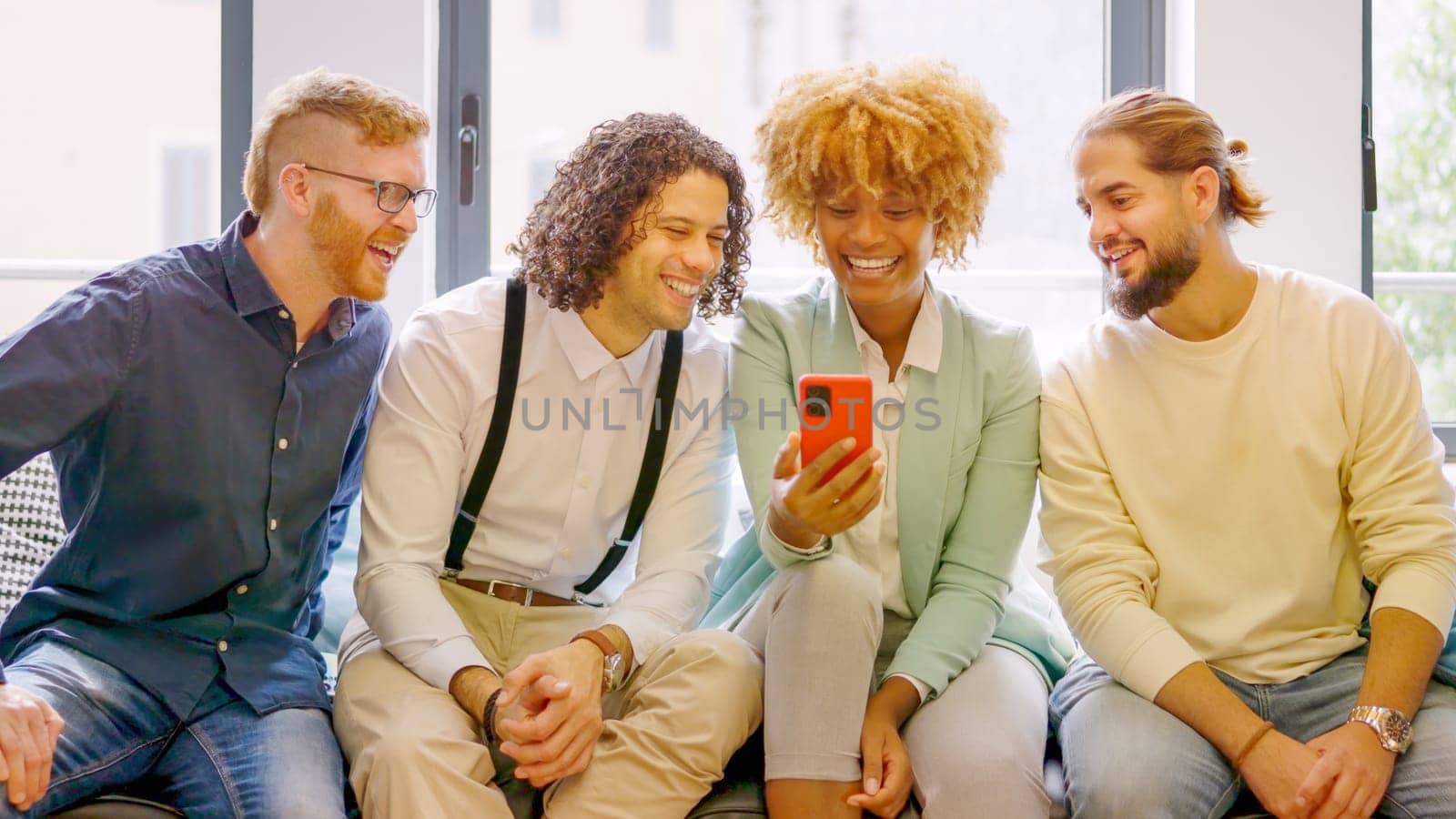 Multi-ethnic coworkers using phone sitting relaxed during a break