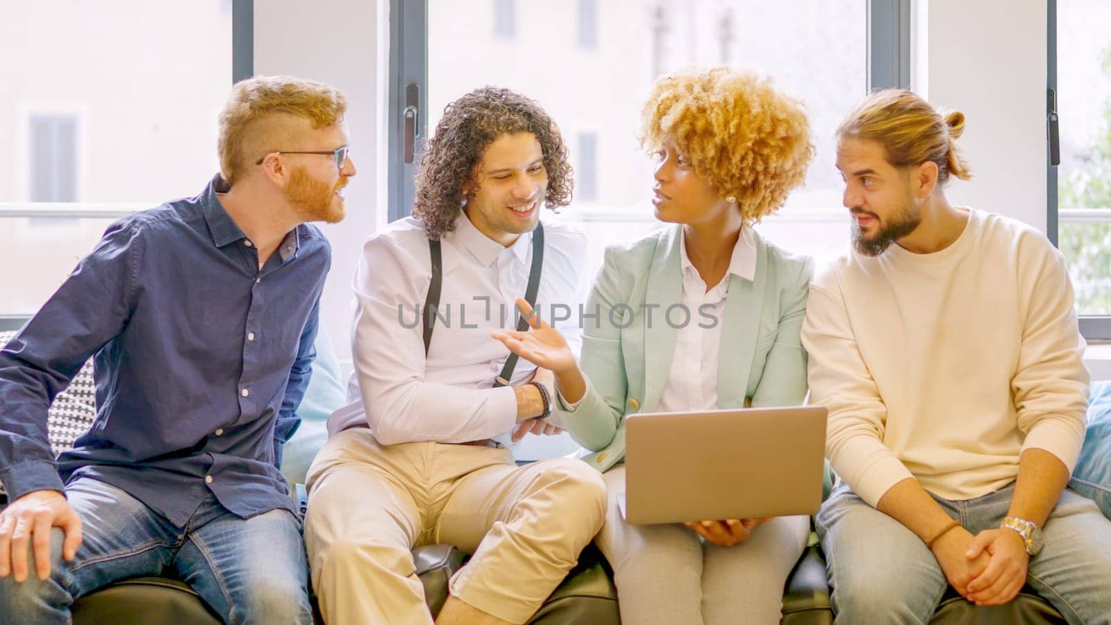 African woman talking to colleagues using laptop sitting comfortable in a coworking