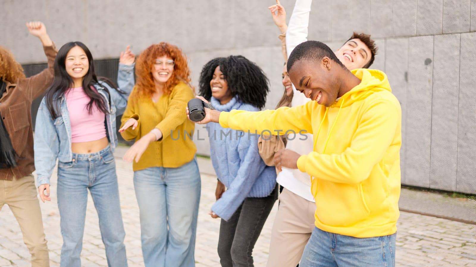 Group of multi-ethnic young friends dancing in the street using a portable speaker