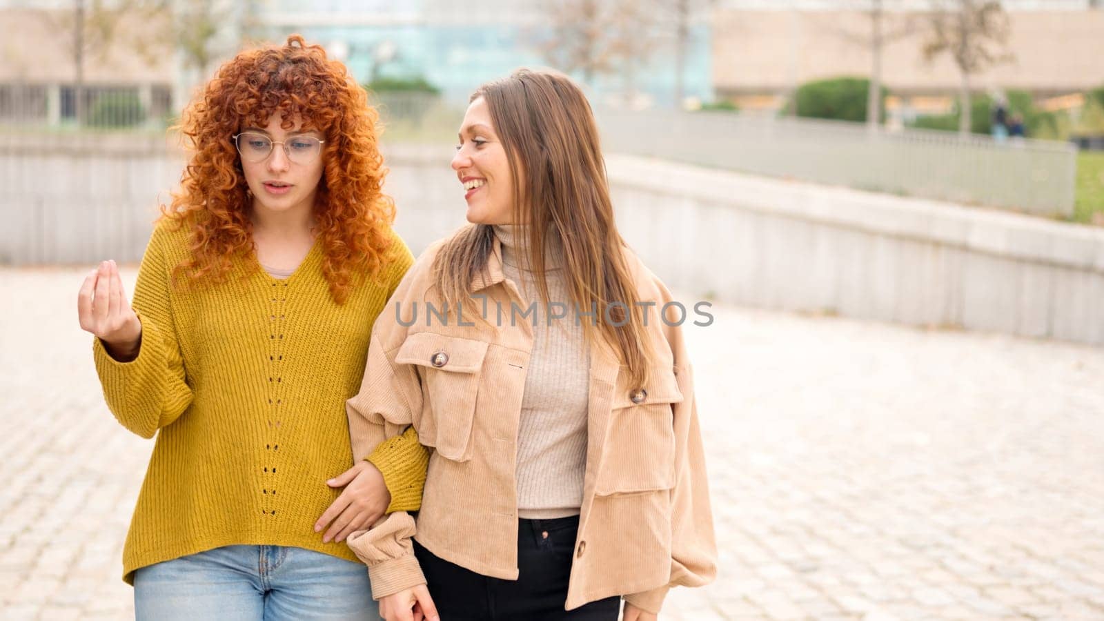 Female friends walking relaxed together and talking along the street