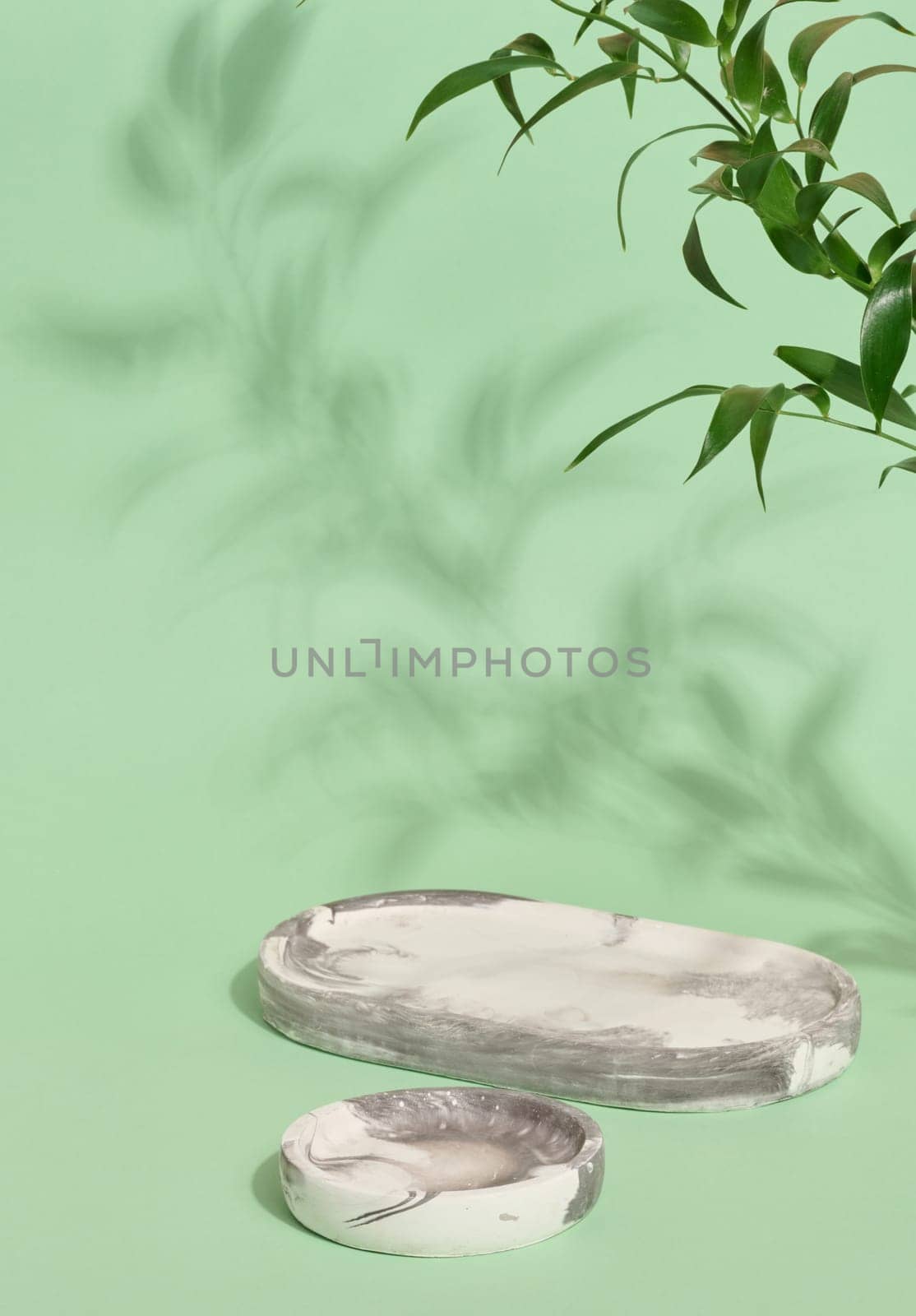 Empty round white marble stand on a green background, a place to display cosmetics and products