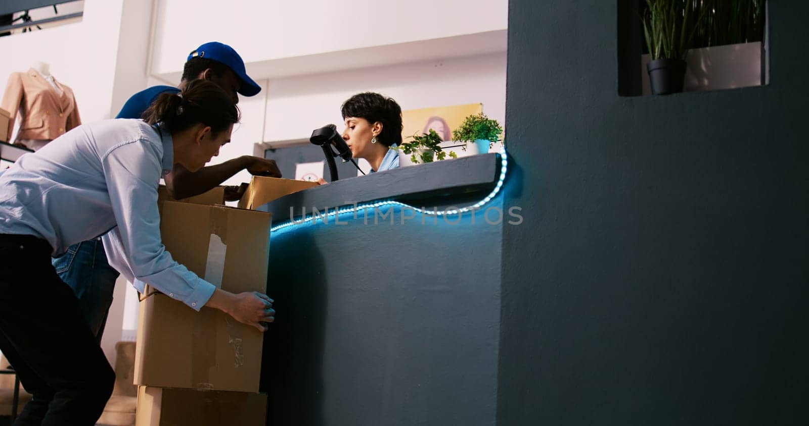 African american courier showing shipment report to worker, discussing online orders details in clothing store. Manager standing at counter desk, preparing packages for shipping in modern boutique