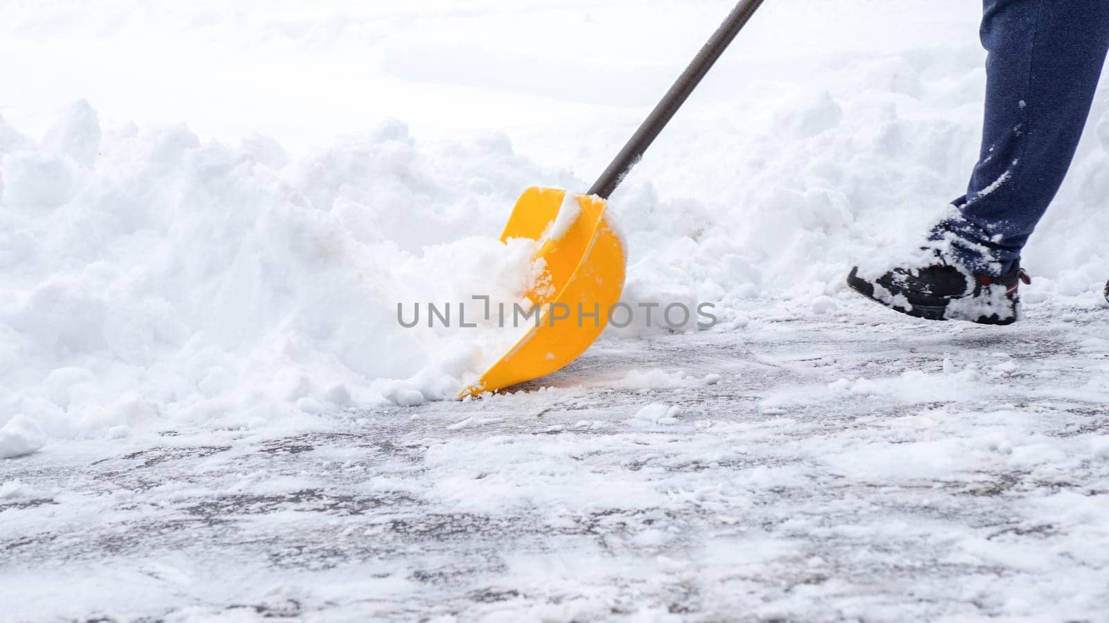 Man shoveling snow off of his driveway after a winter storm in Canada. Man with snow shovel cleans sidewalks in winter. Winter time. by JuliaDorian