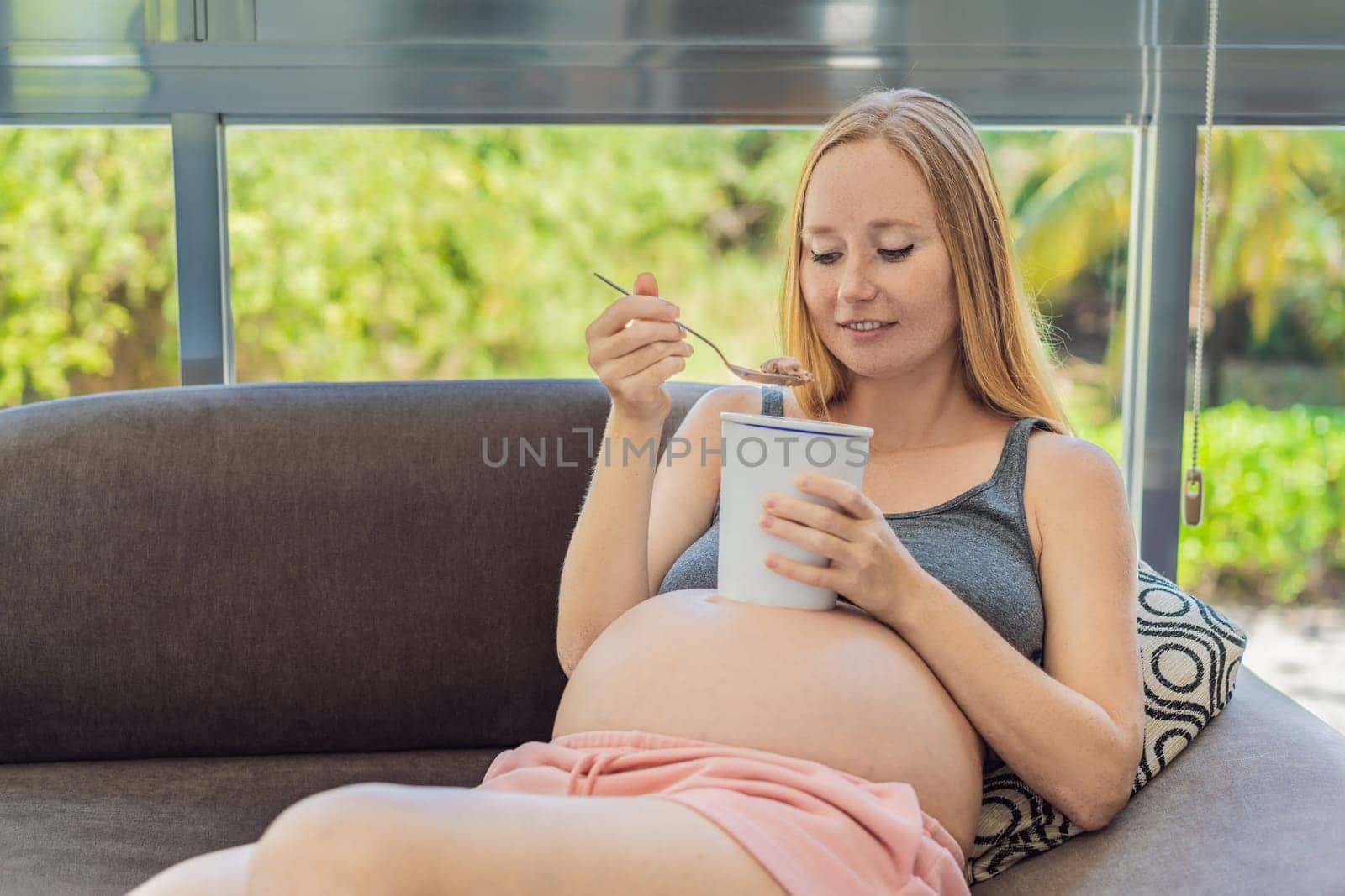 Happy pregnant young woman eating ice cream.