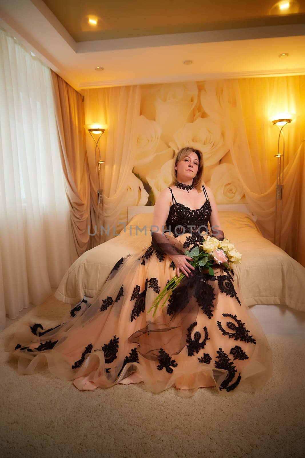 Portrait of beautiful elegant woman in in a royal dress indoors in nice room in evening time. Middle-aged adult lady in a romantic setting