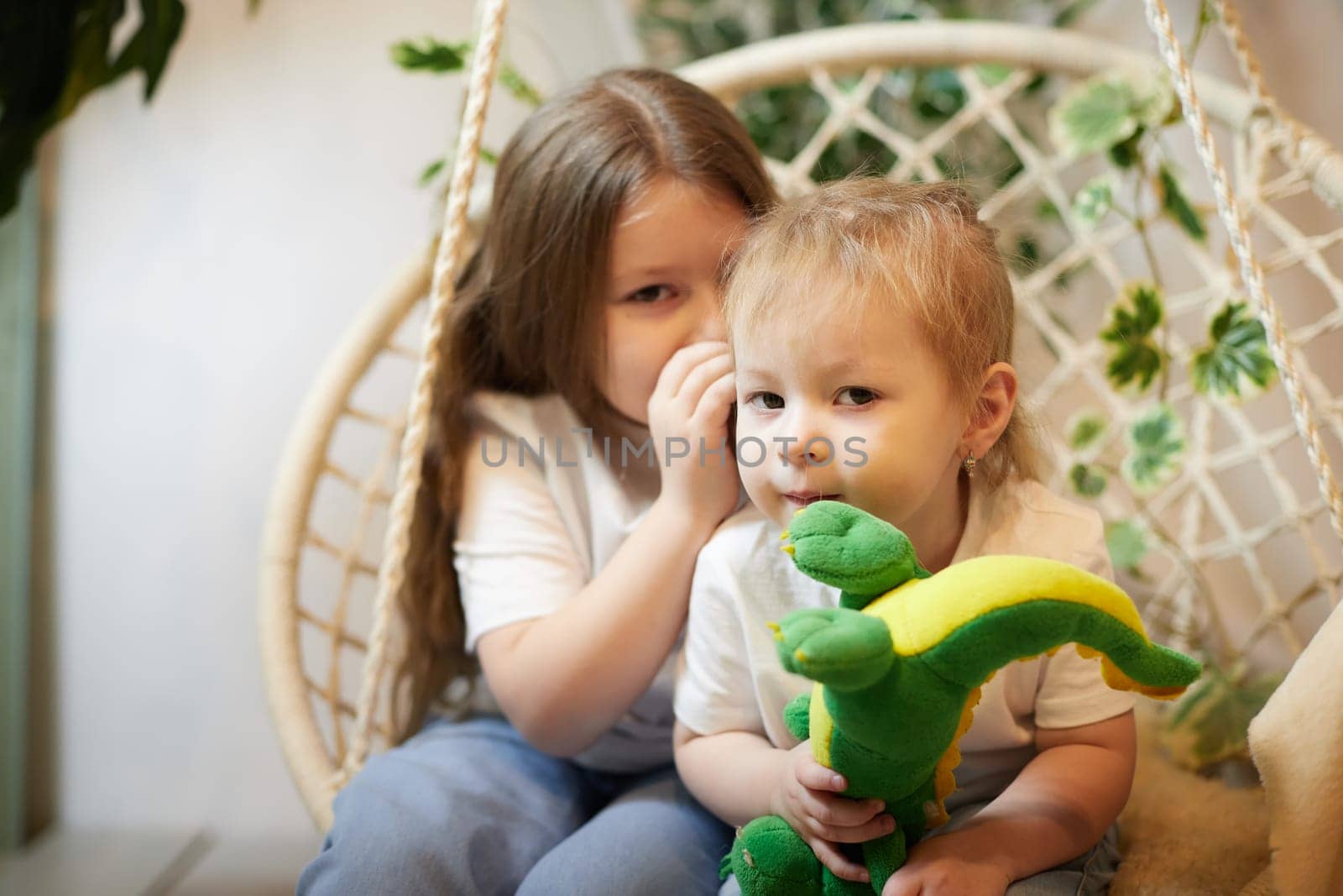 Happy time concept. Girls Sisters in chair and having fun. Female Preschooler and teenager playing relaxing in room by keleny