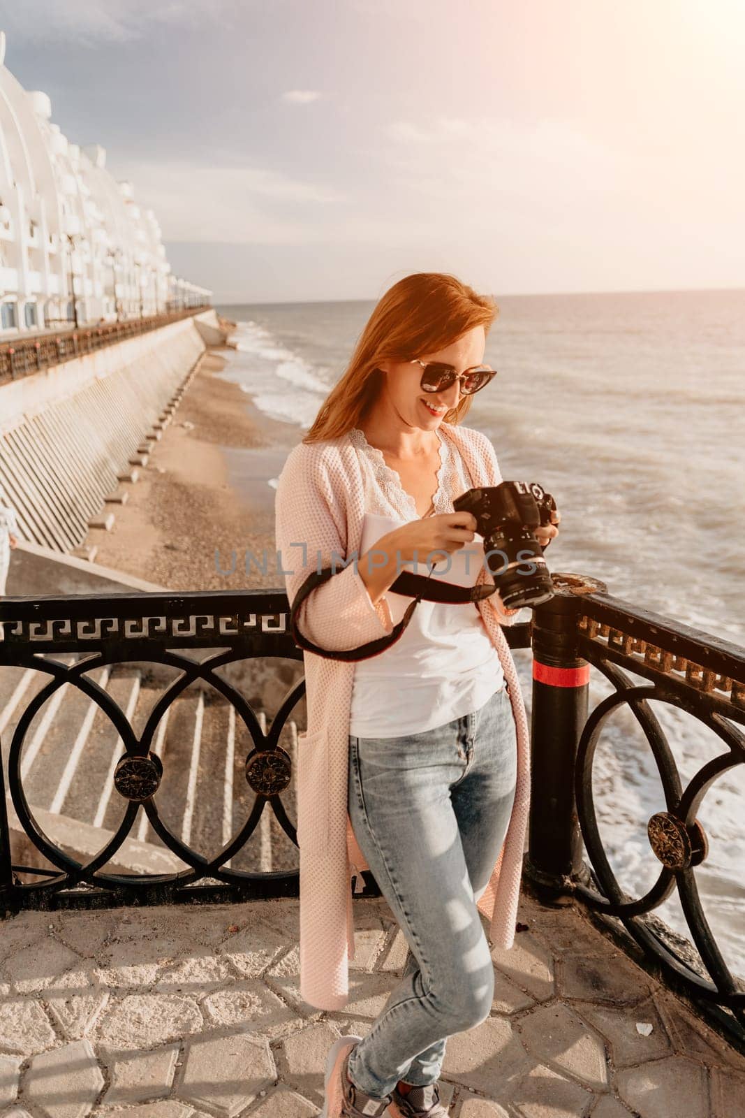 Woman summer travel sea. Happy tourist enjoy taking picture outdoors for memories. Carefree woman traveler posing on beach at sea on sunset, sharing travel adventure journey. Holiday vacation concept. by panophotograph