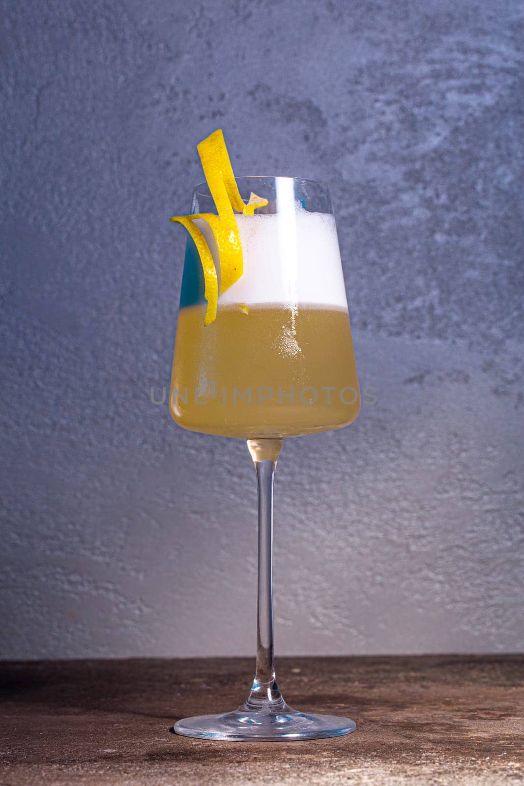 Sophisticated champagne cocktail with lemon twist on wooden table, blue background. Perfect for special occasions and toasting moments.