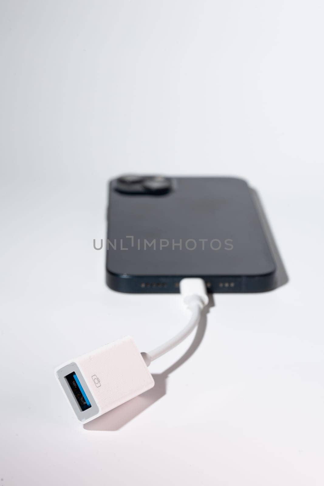 A smartphone connected to a USB adapter as a portable communication device for port-based data transfer.