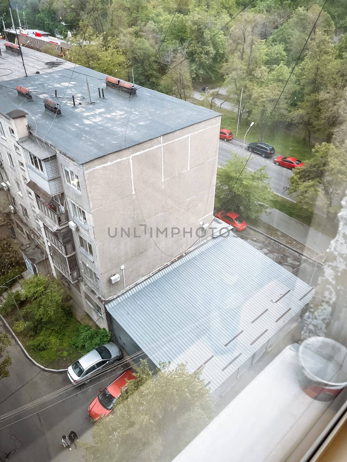 An urban landscape with lots of red cars in the courtyard of an apartment building.