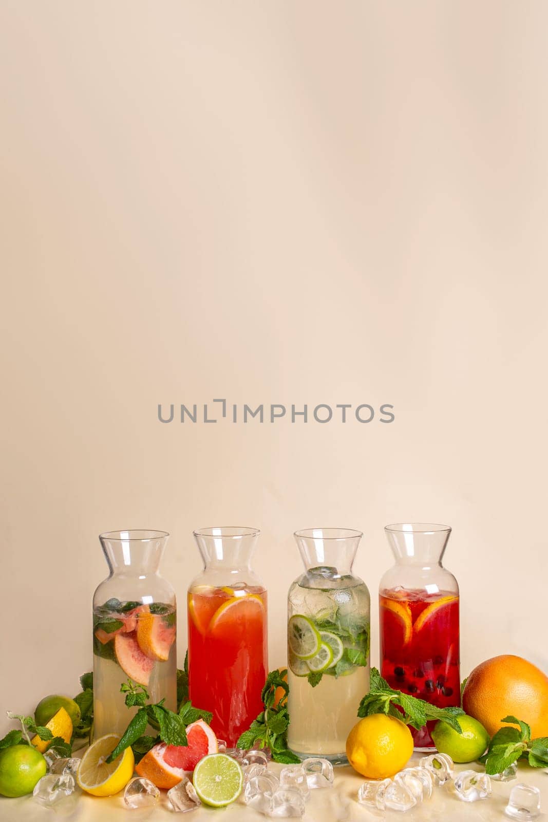 Assorted cold lemonades in glass jugs on an ochre background. photos for the menu.