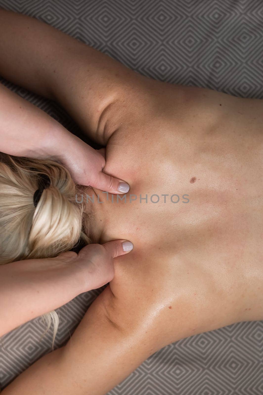 Top view of a woman undergoing a cervical-neck massage. Vertical photo. by mrwed54
