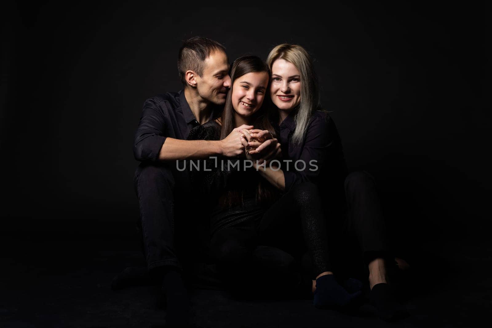 cute little girl and her beautiful young parents looking at camera and smiling.