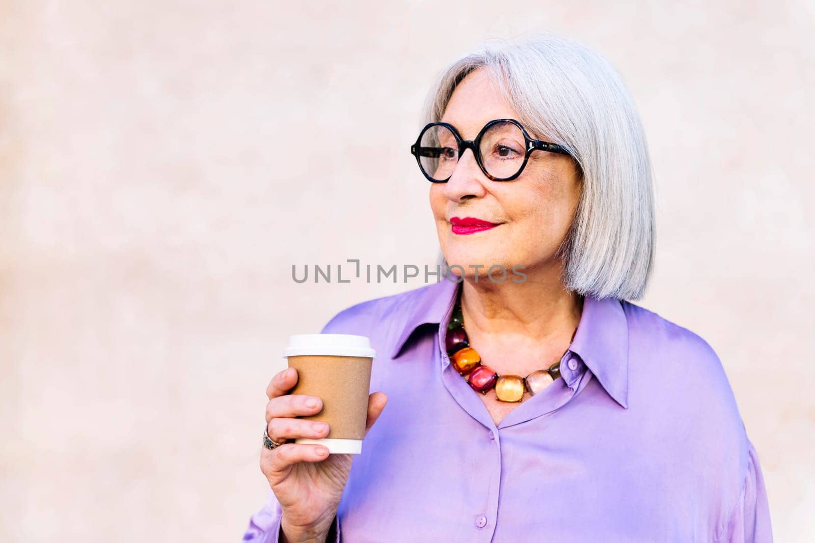 smiling senior woman holding a takeaway coffee in her hand, concept of elderly people leisure and active lifestyle, copy space for text
